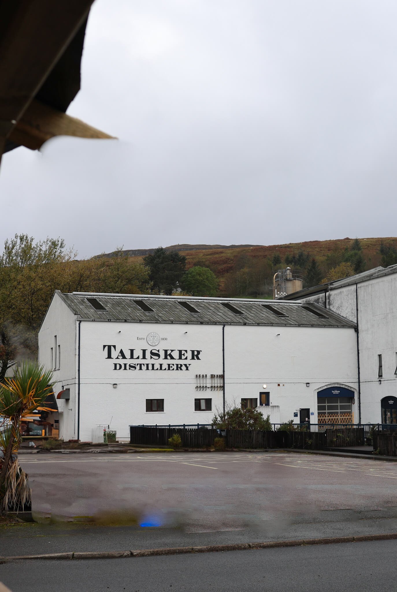 Traditional whitewashed whisky distillery with Talisker signpost on the Isle of Skye