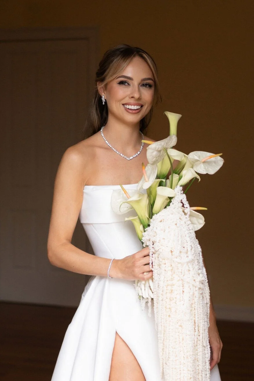 A woman in a white wedding dress holding a bouquet of white calla lilies