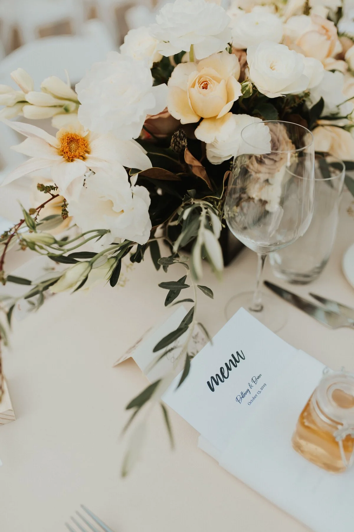 A wedding reception table with flowers, a wine glass, and a menu.