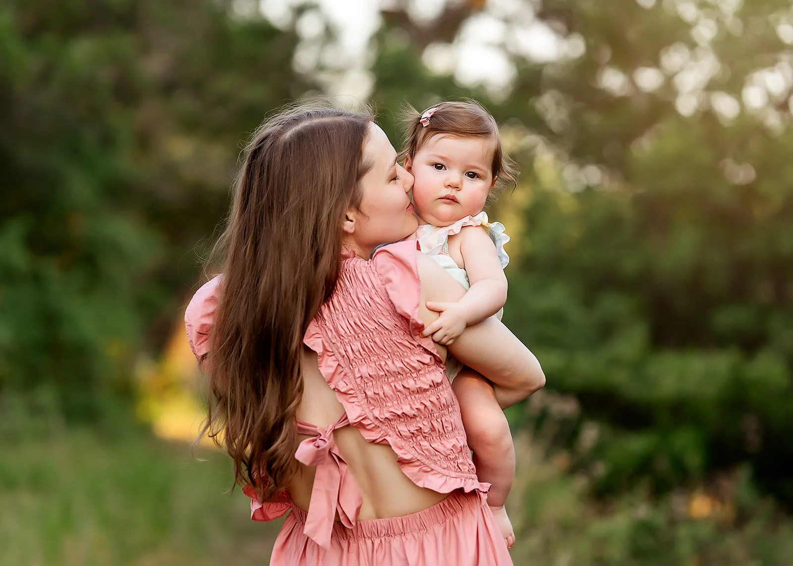 Mom kissing baby at sunset in park in Austin