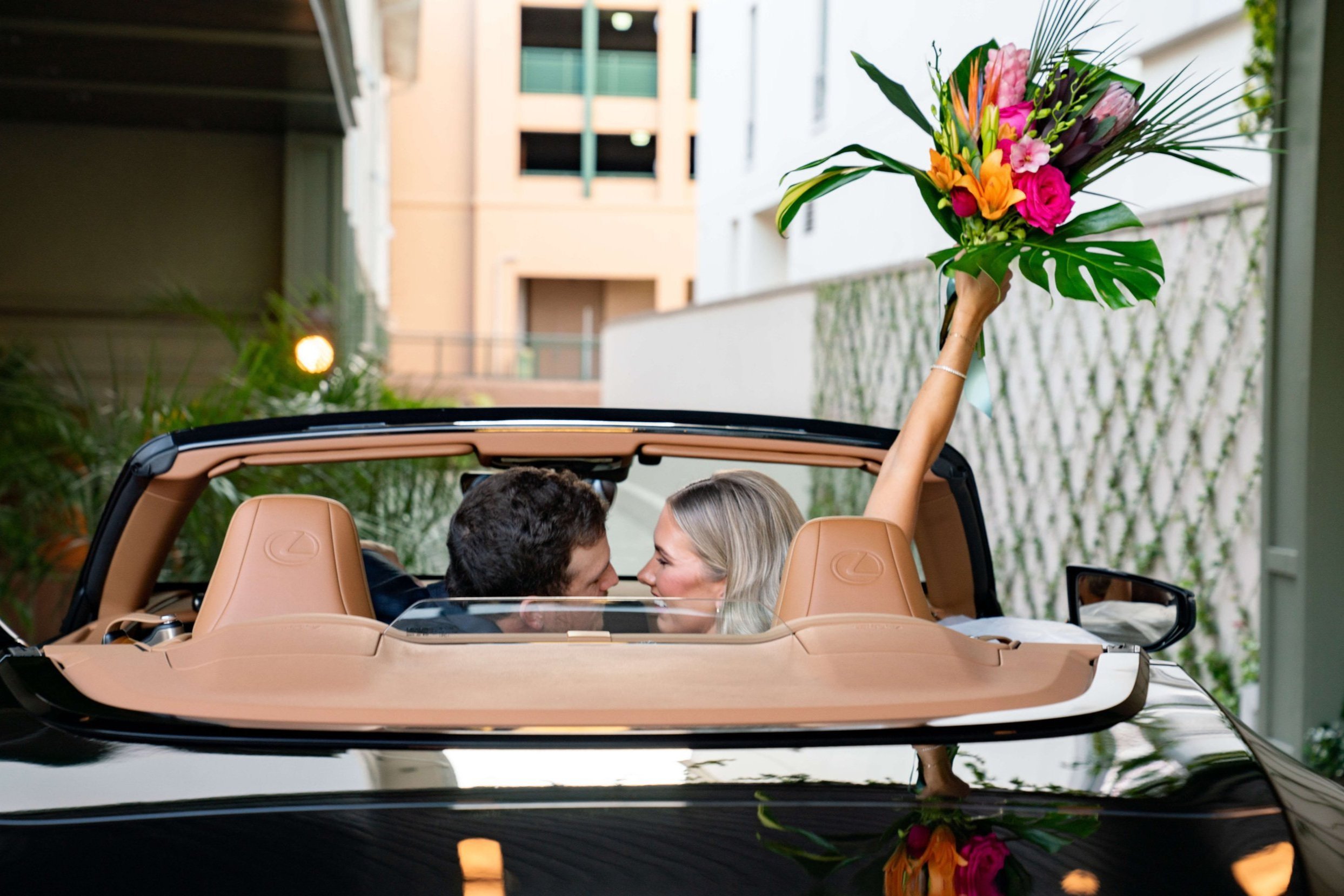 Bride and groom driving away in car