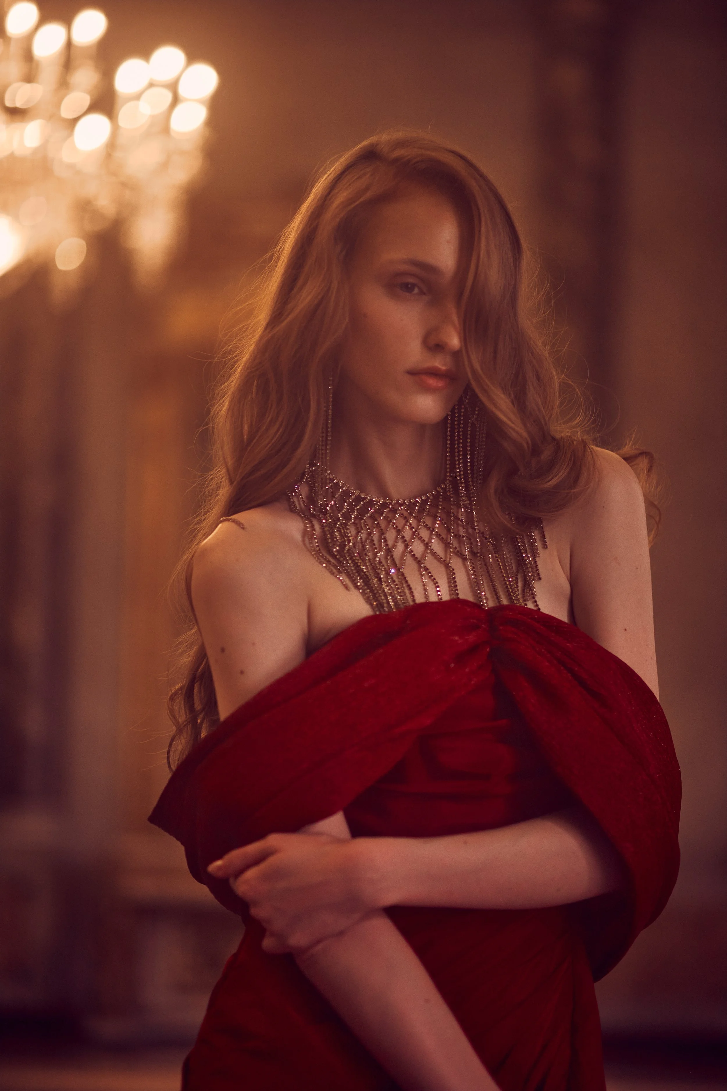 Warm tones portrait of a female model with wavy ginger hair, wearing a red sparkle dress, shinny necklace with stones, photographed in Palazzo Serbelloni in Milan, Nelson Stein Photography, Lisbon Portugal