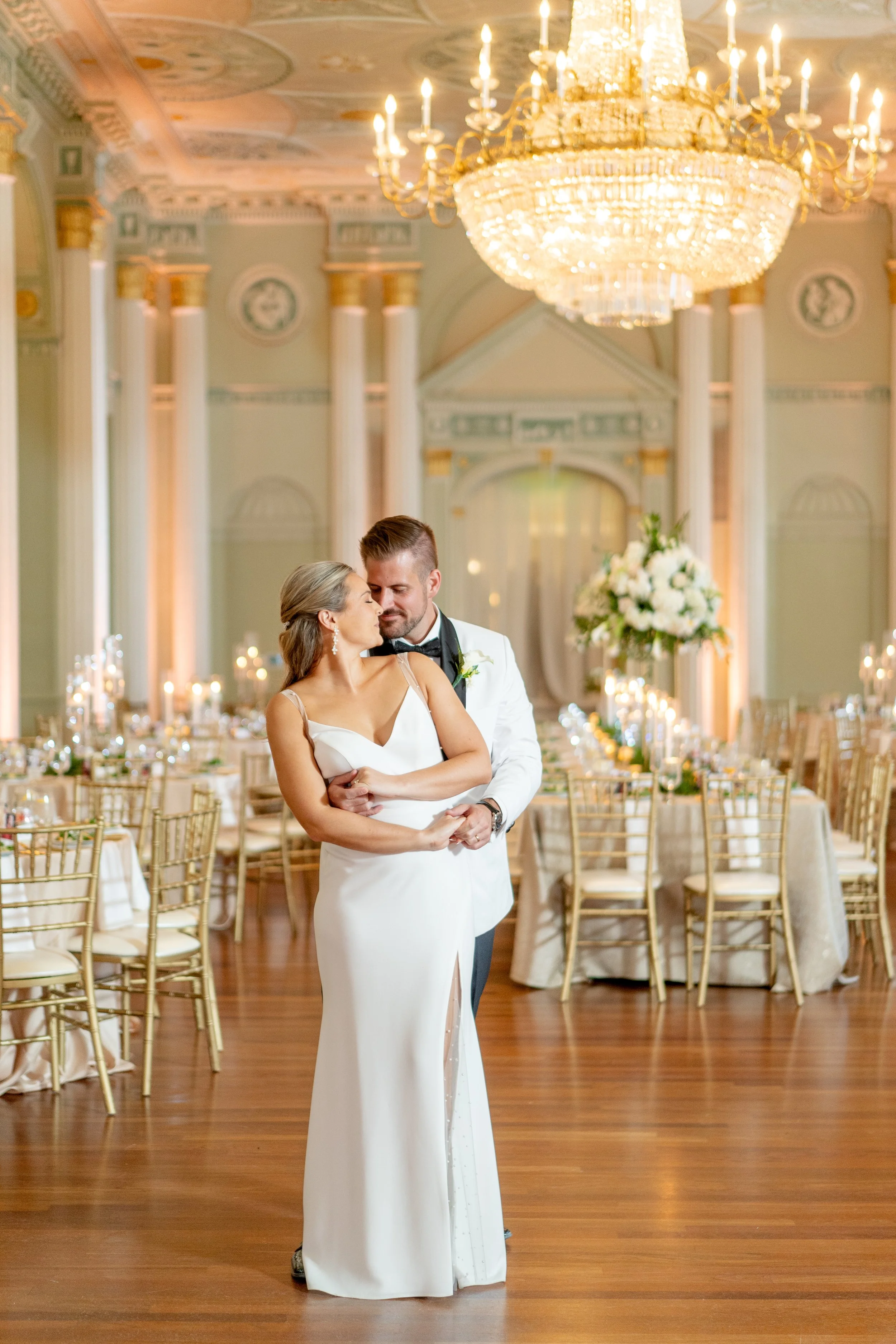 A bride and groom sharing a romantic moment on the dance floor at their wedding reception at the Biltmore Ballrooms in an elegant, chandelier-lit ballroom.