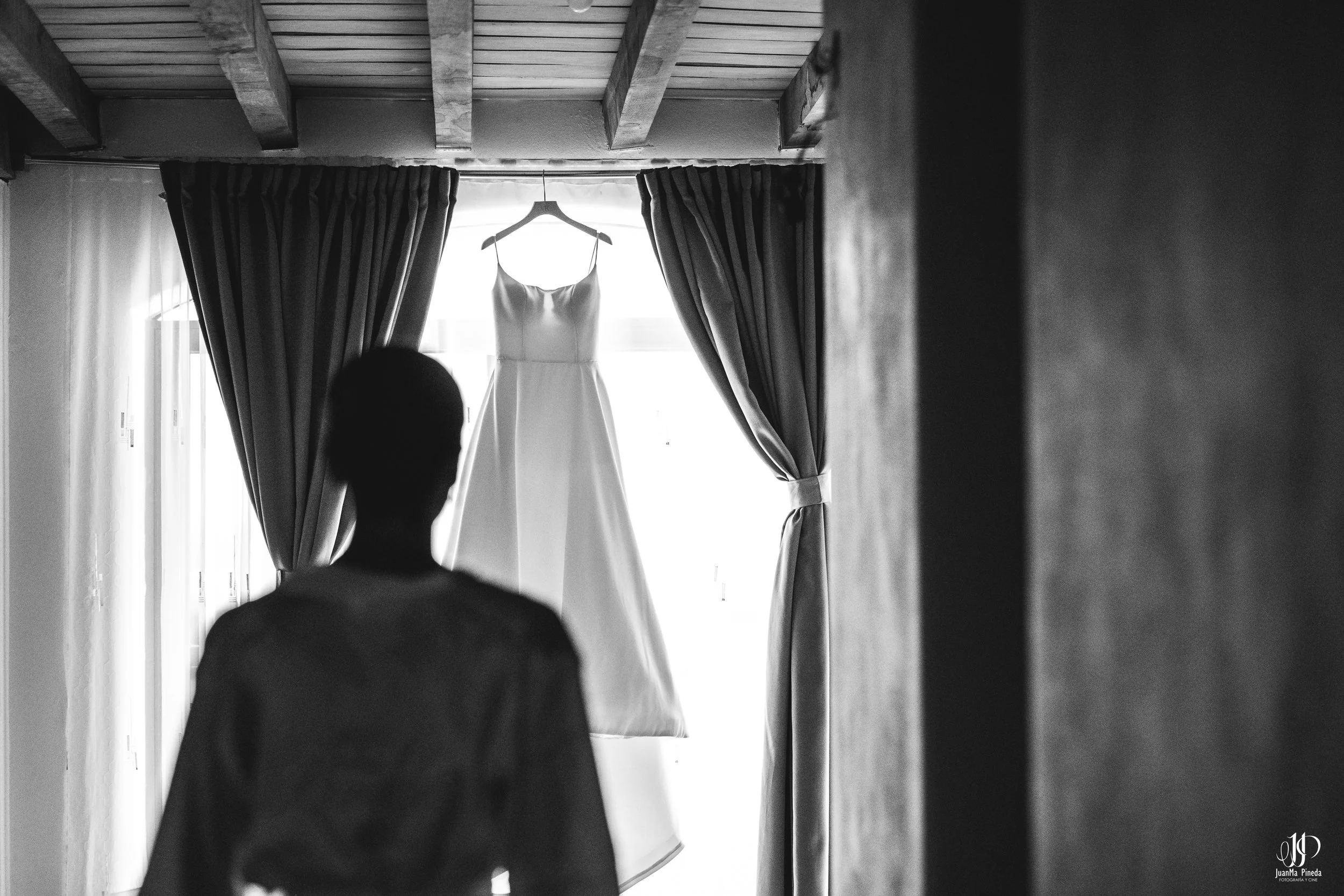 Novia contemplando su vestido suspendido en la luz suave del amanecer en El Desván del Recuerdo – el inicio perfecto para tu boda destino en Atotonilco El Alto, Jalisco