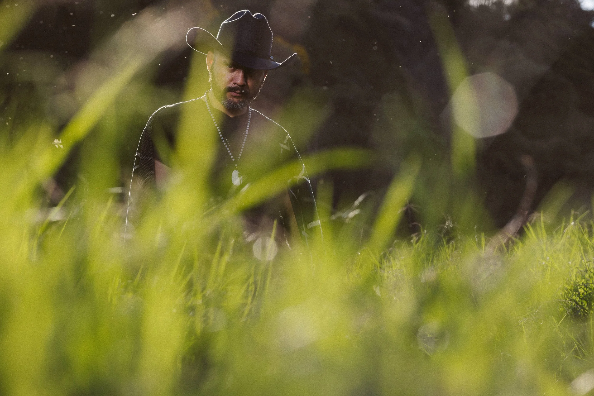 Hombre con sombrero de vaquero en un campo con hierba alta.