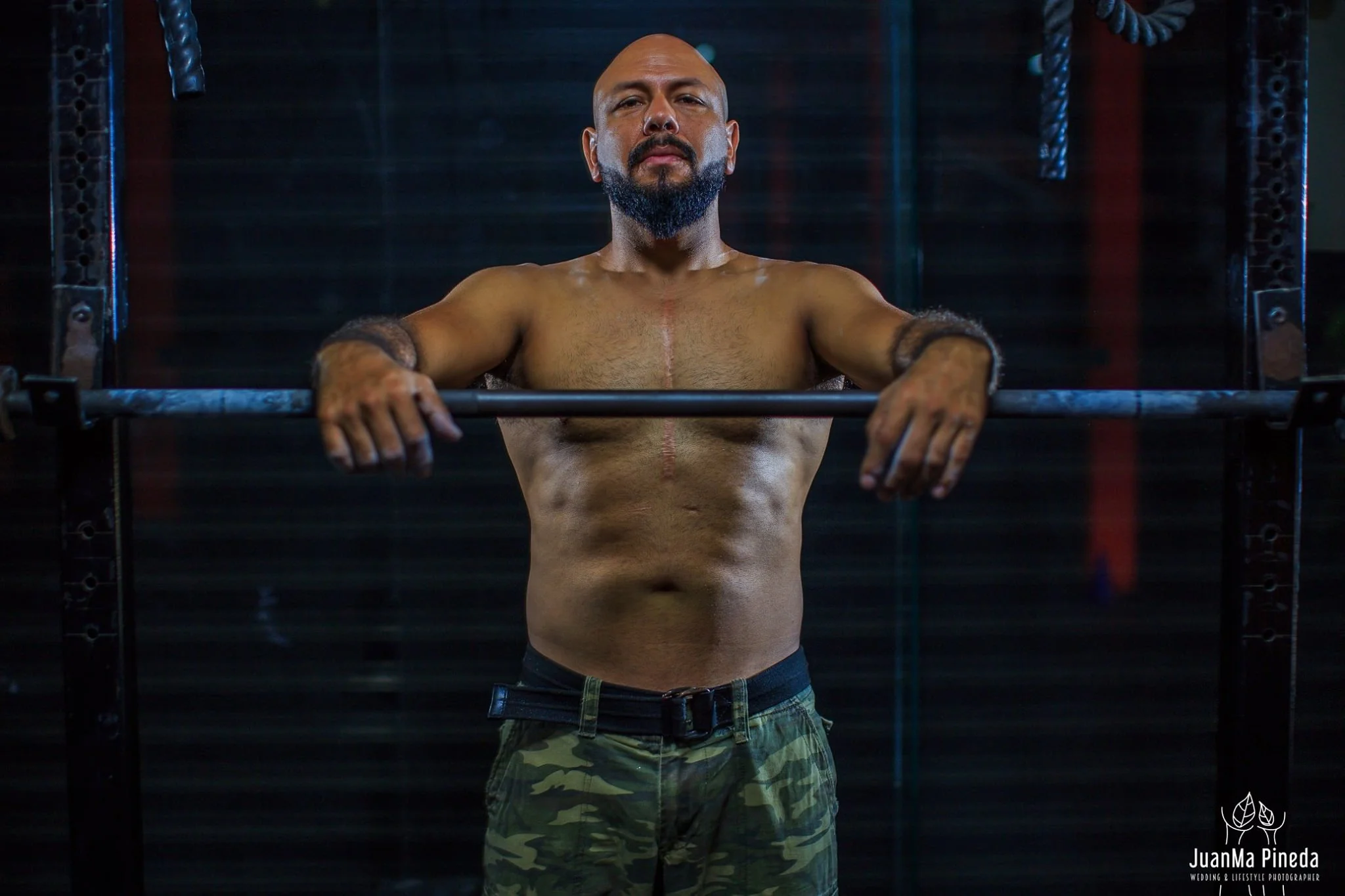 Hombre musculoso en un gimnasio con pantalones de camuflaje.