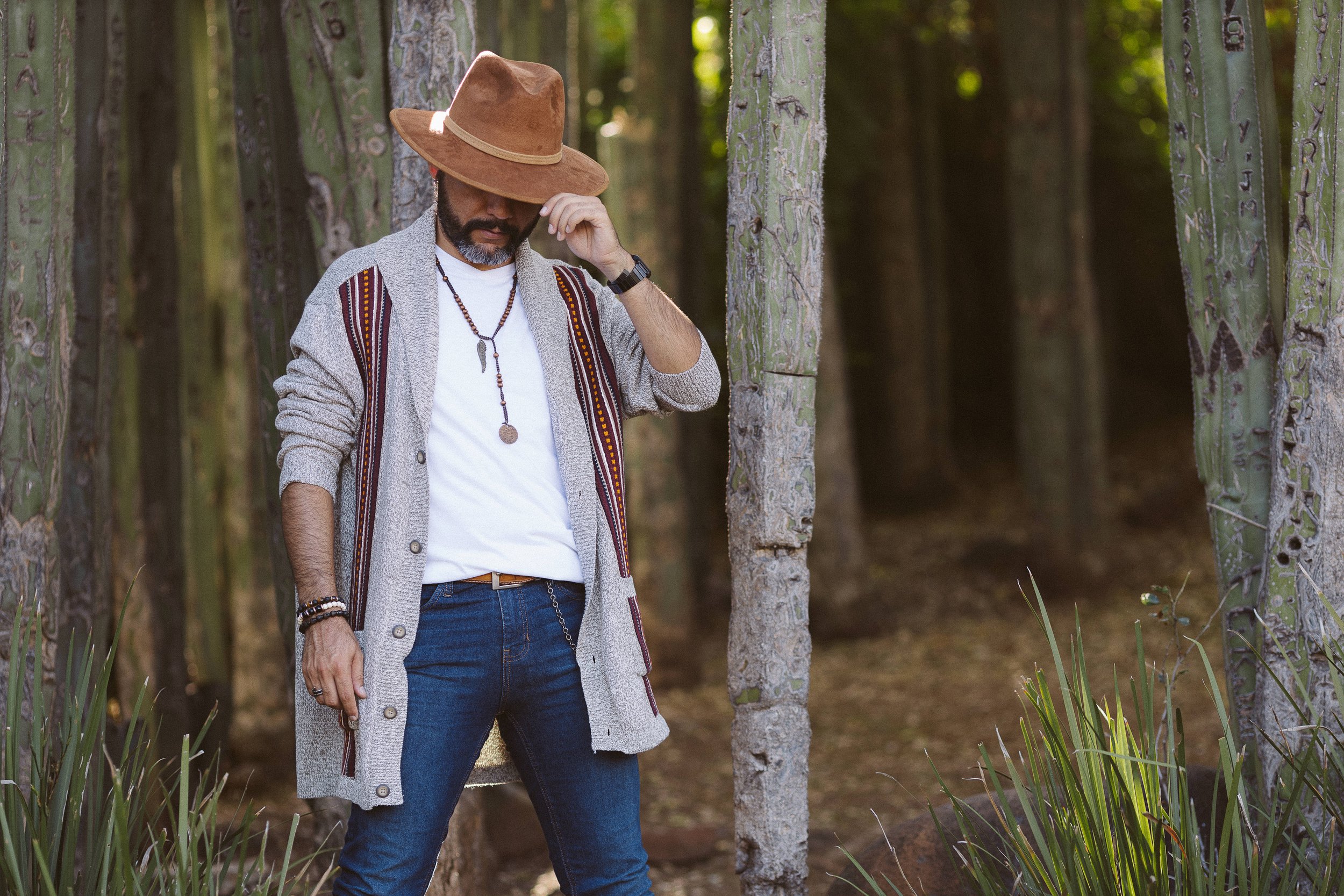Hombre con sombrero marrón y suéter gris en bosque