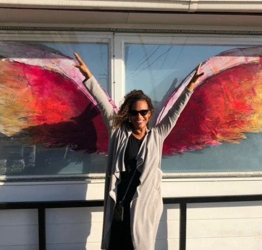 Monique Mannen standing beside a vibrant abstract artwork, reflecting her passion for health, longevity, and living with purpose.
