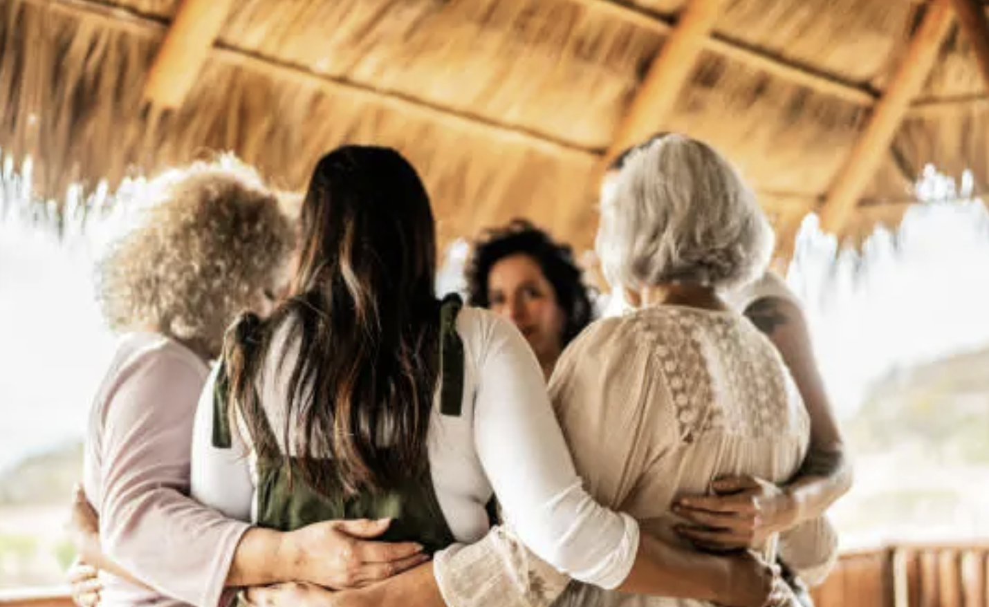 People standing together with arms around each other under a wooden roof