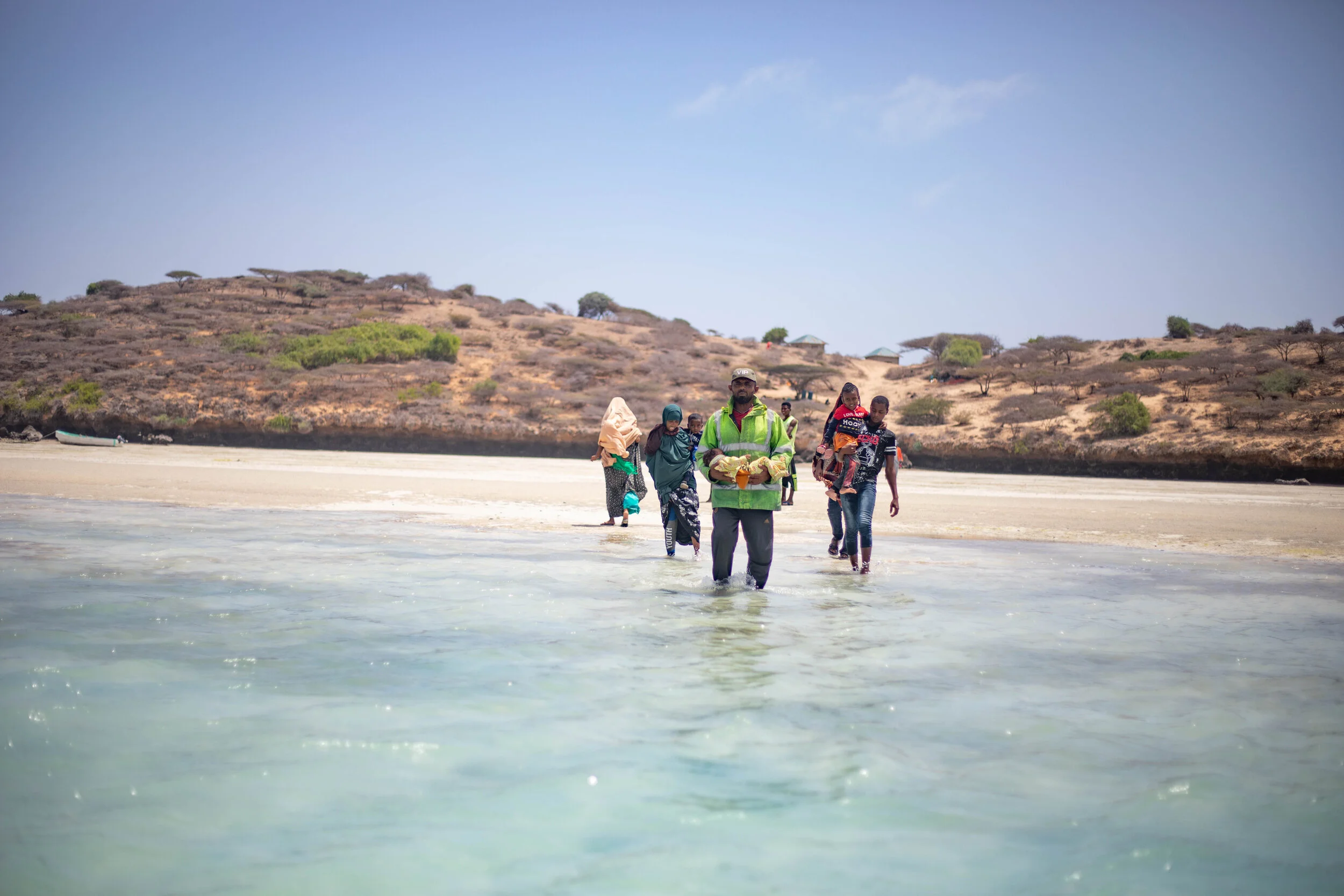 A man helps a woman carry her child on to the boat as she travels to Kismayo for medical reasons. 