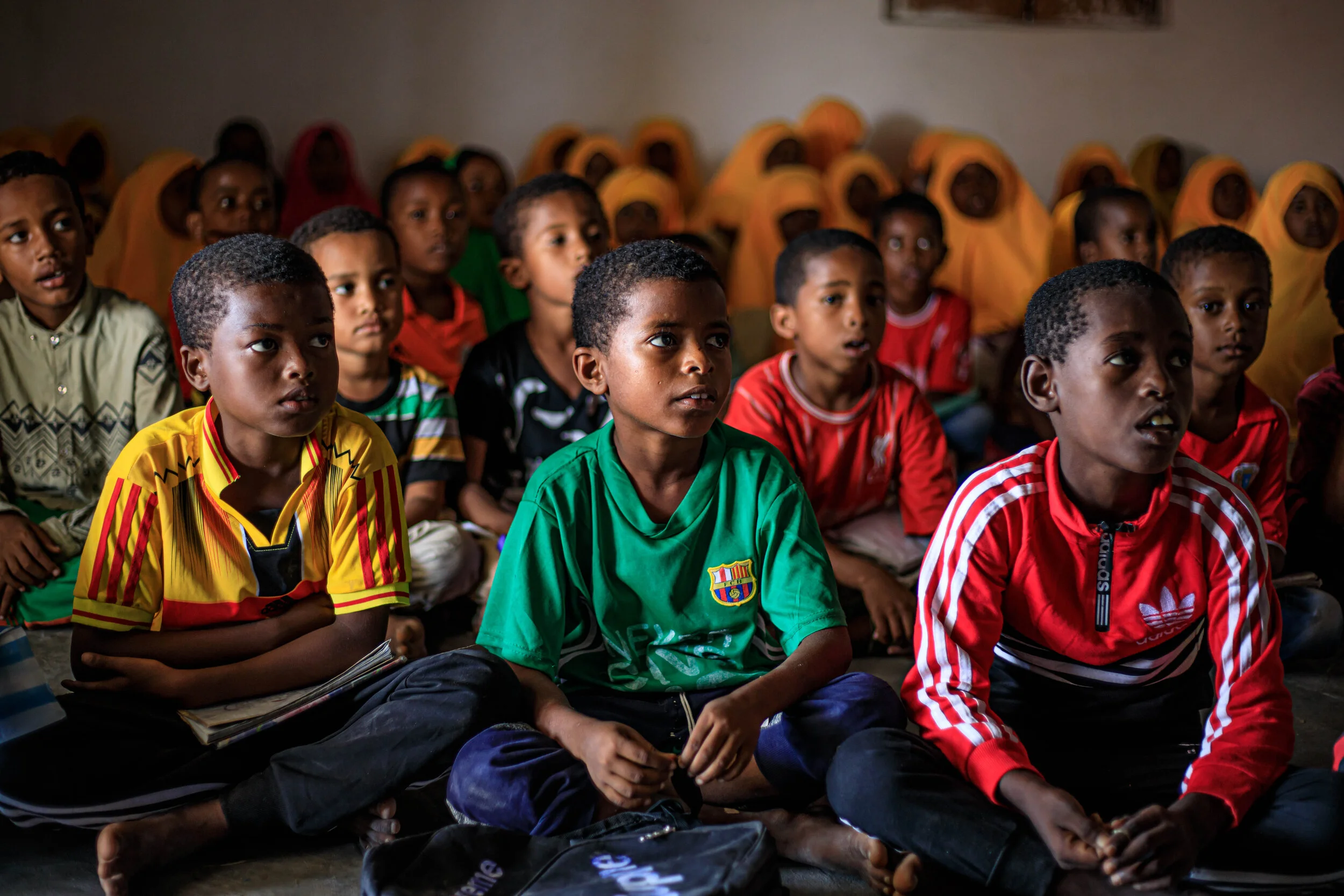 Pupils sit on the floor as they listen to their teacher at a makeshift school in Mudawa Island. 