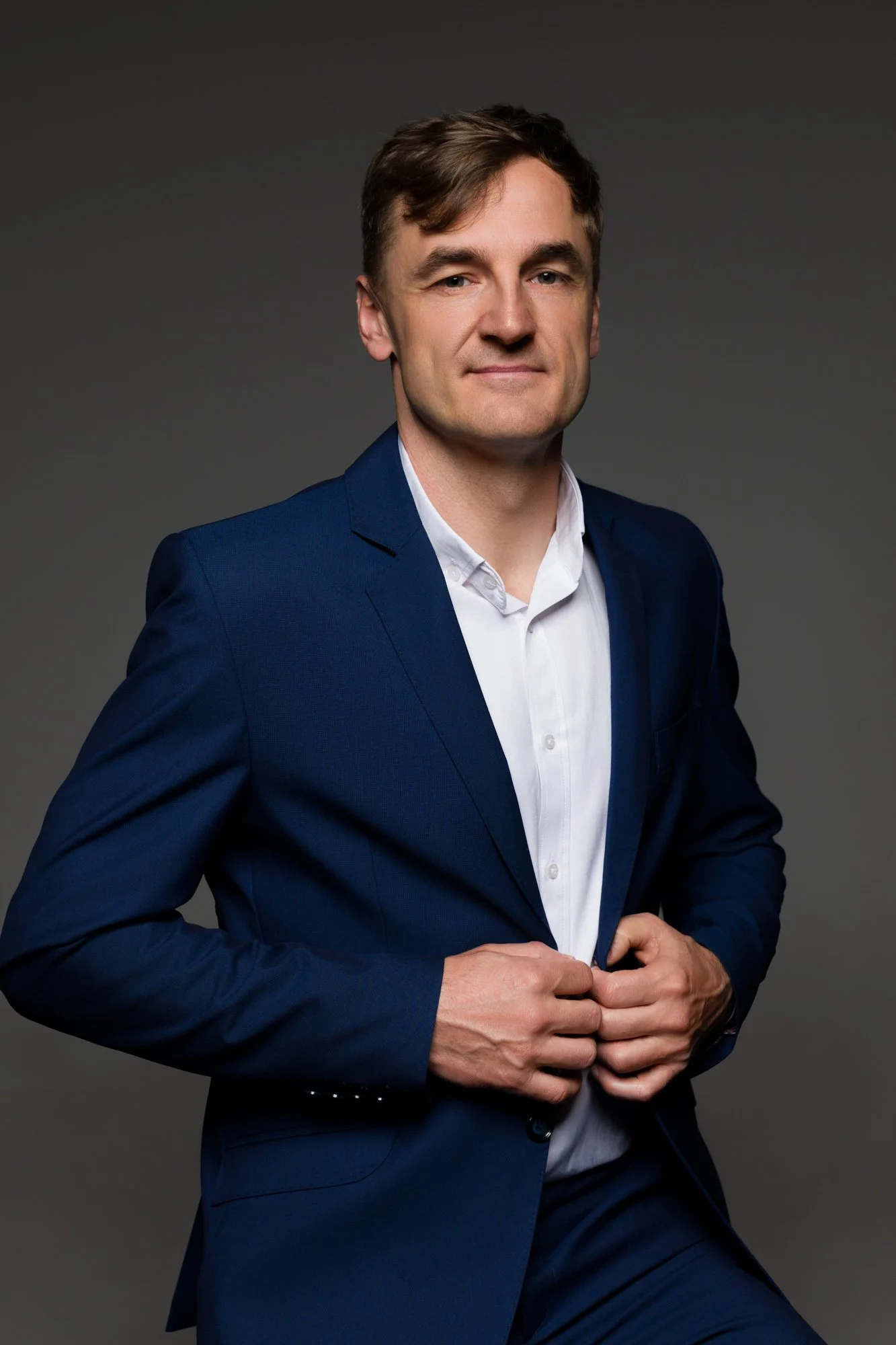CEO mężczyzna w średnim wieku pozuje do  portretu biznesowego w granatowych garniturze i białej koszuli bez krawatu