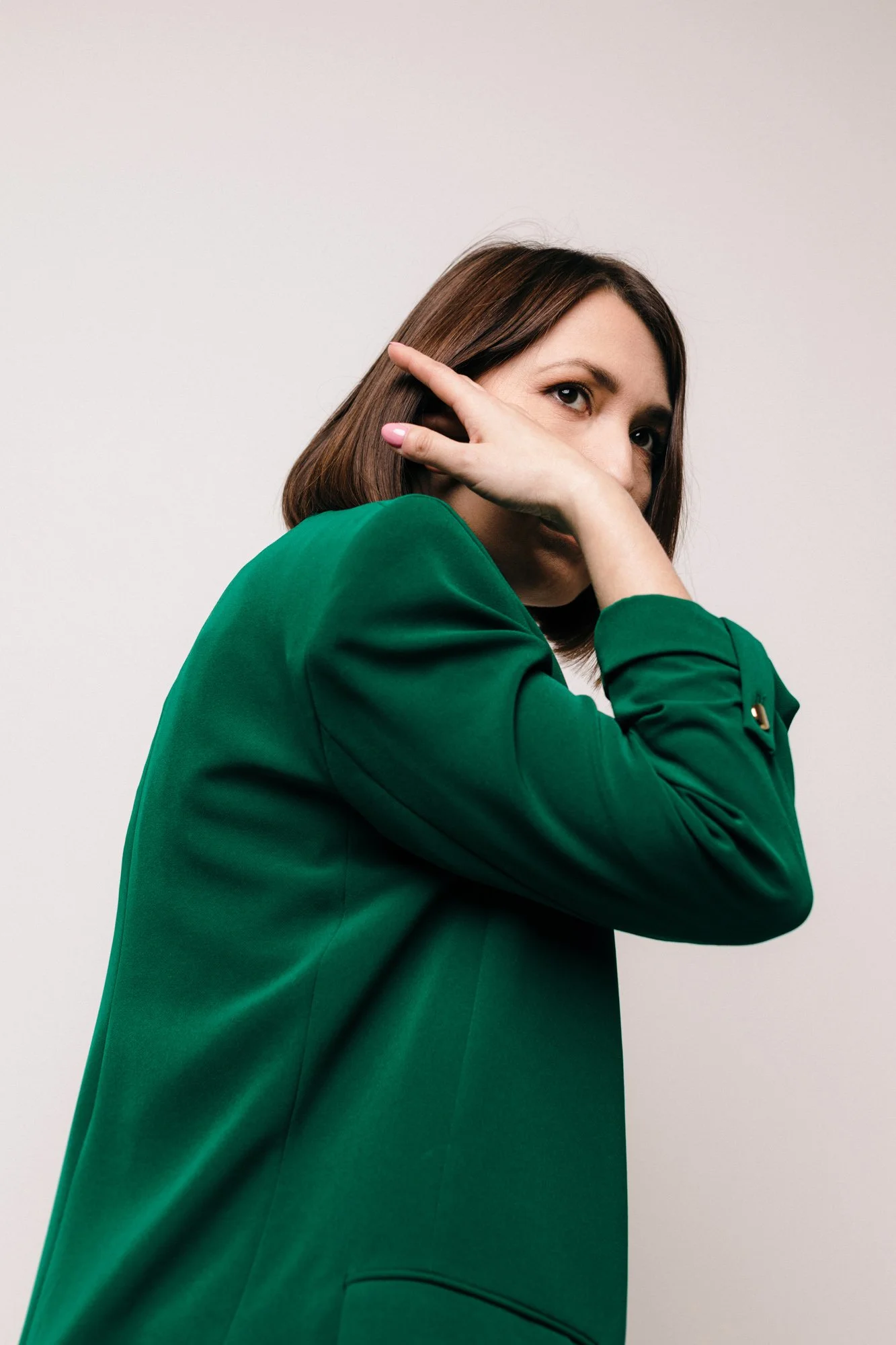 portret kobiety w zielonej marynarce pozuje w studio na białym tle