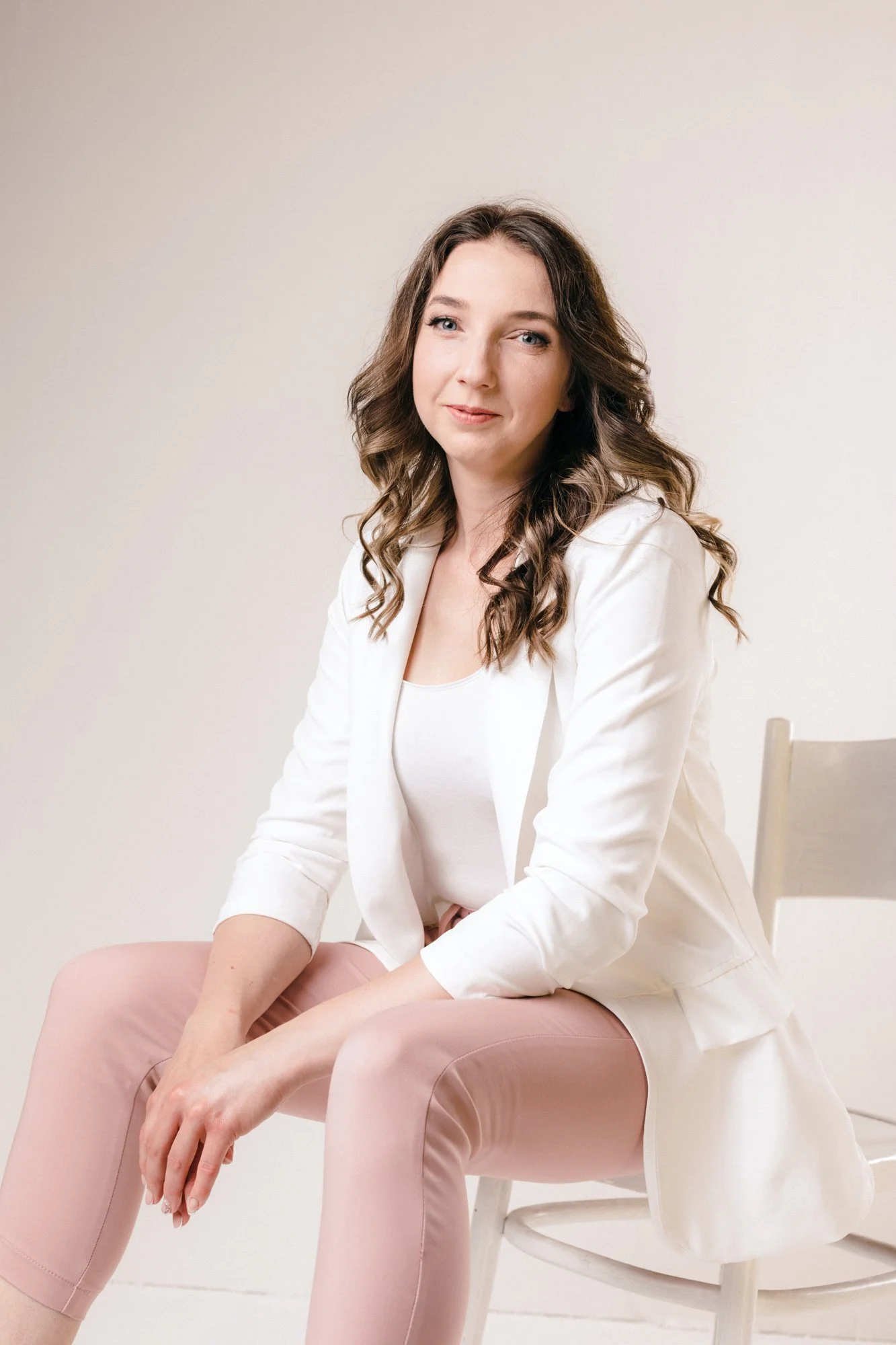 portret kobiety w białej marynarce, siedzi na krześle w studio podczas sesji wizerunkowej