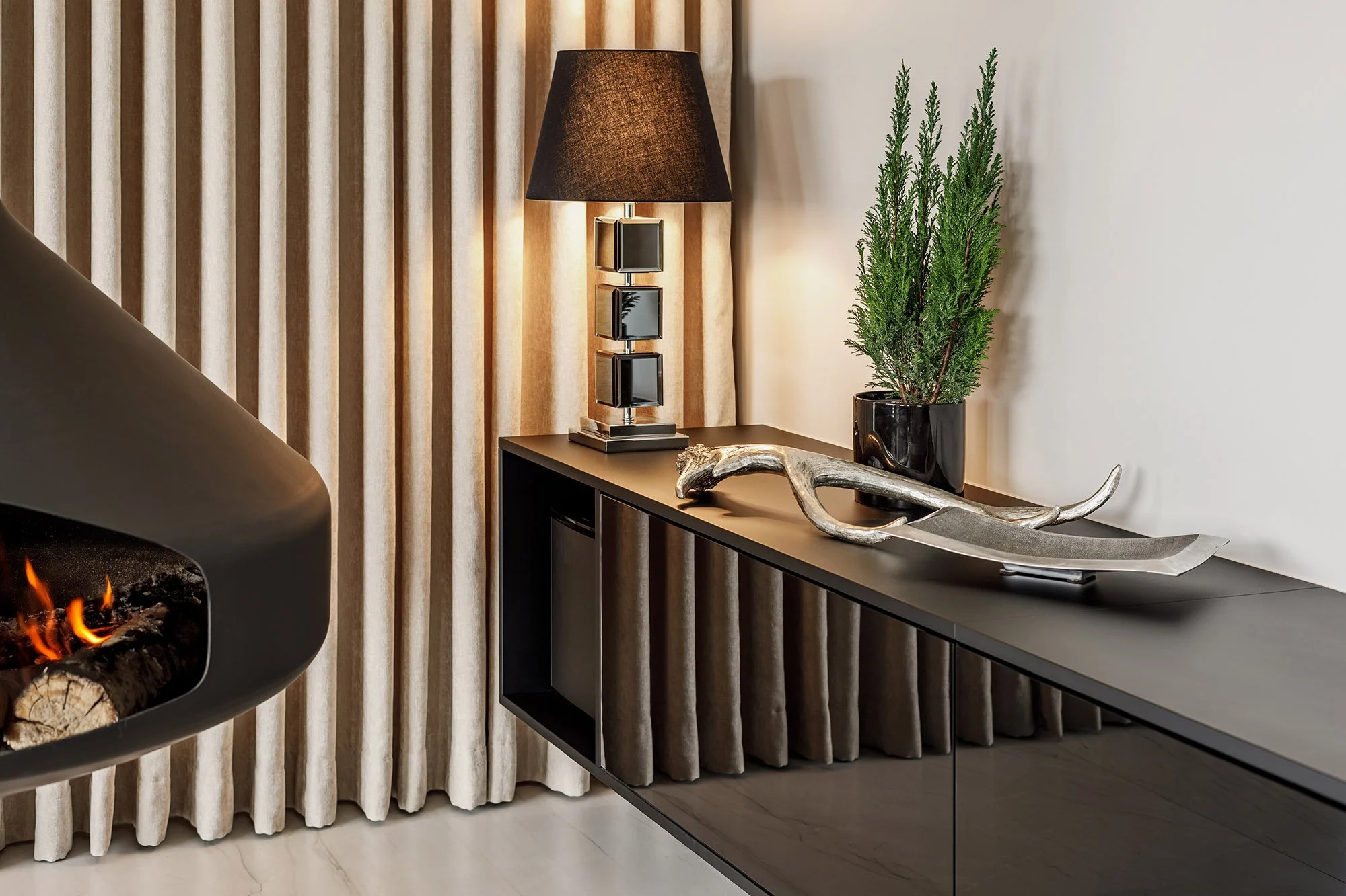 luksusowe wnętrze z czarną szafką i lampą, na tle złotych zasłon