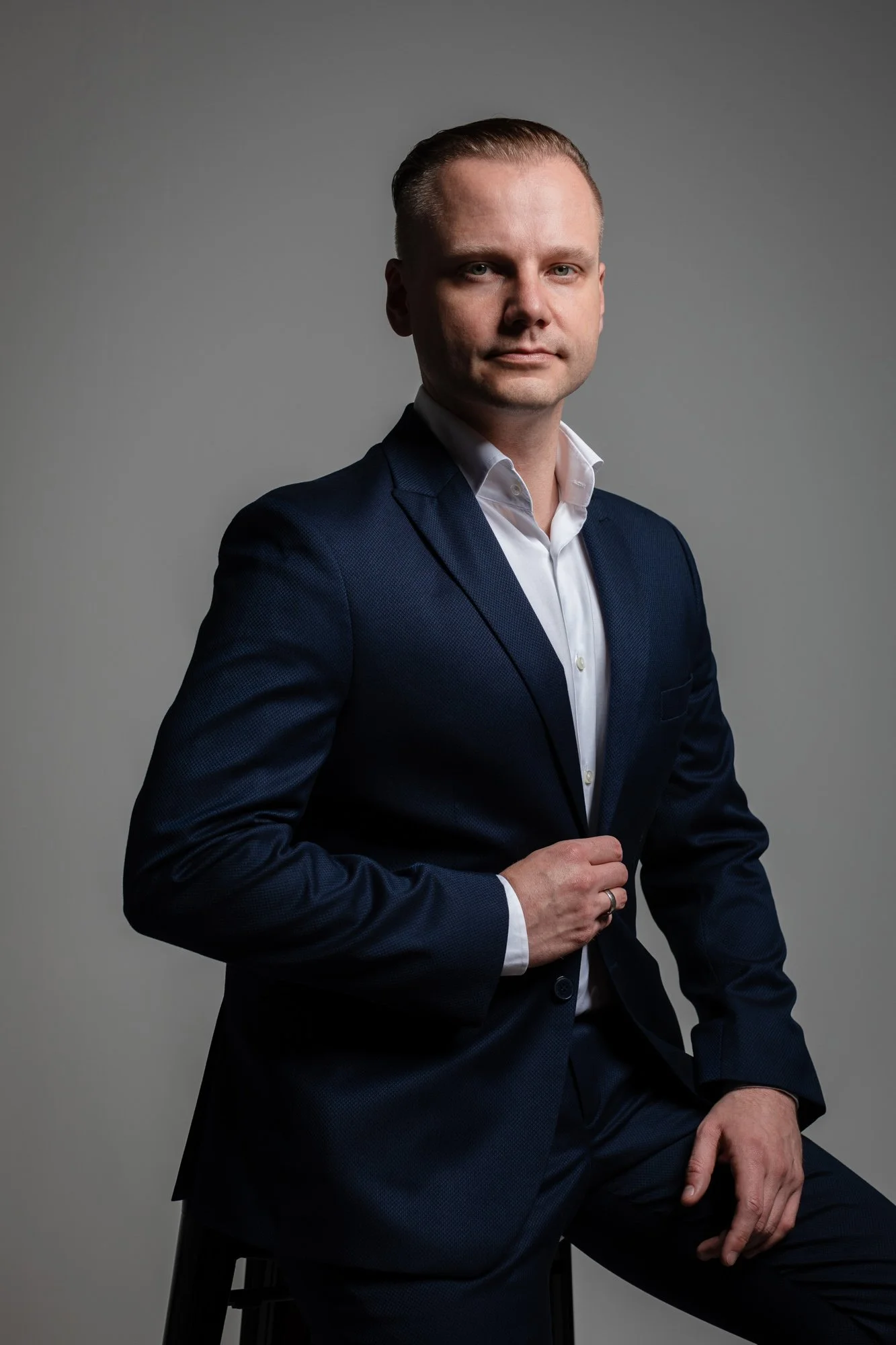 CEO pozujący w czasie sesji wizerunkowej w studio, biała koszula i ciemny garnitur