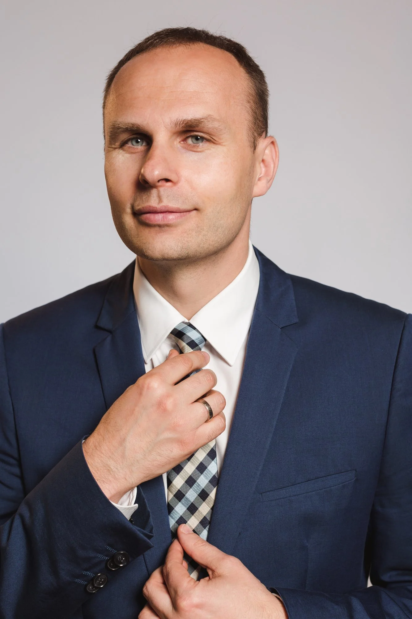 polityk i prawnik w granatowym garniturze poprawia krawat podczas sesji wizerunkowej w studio