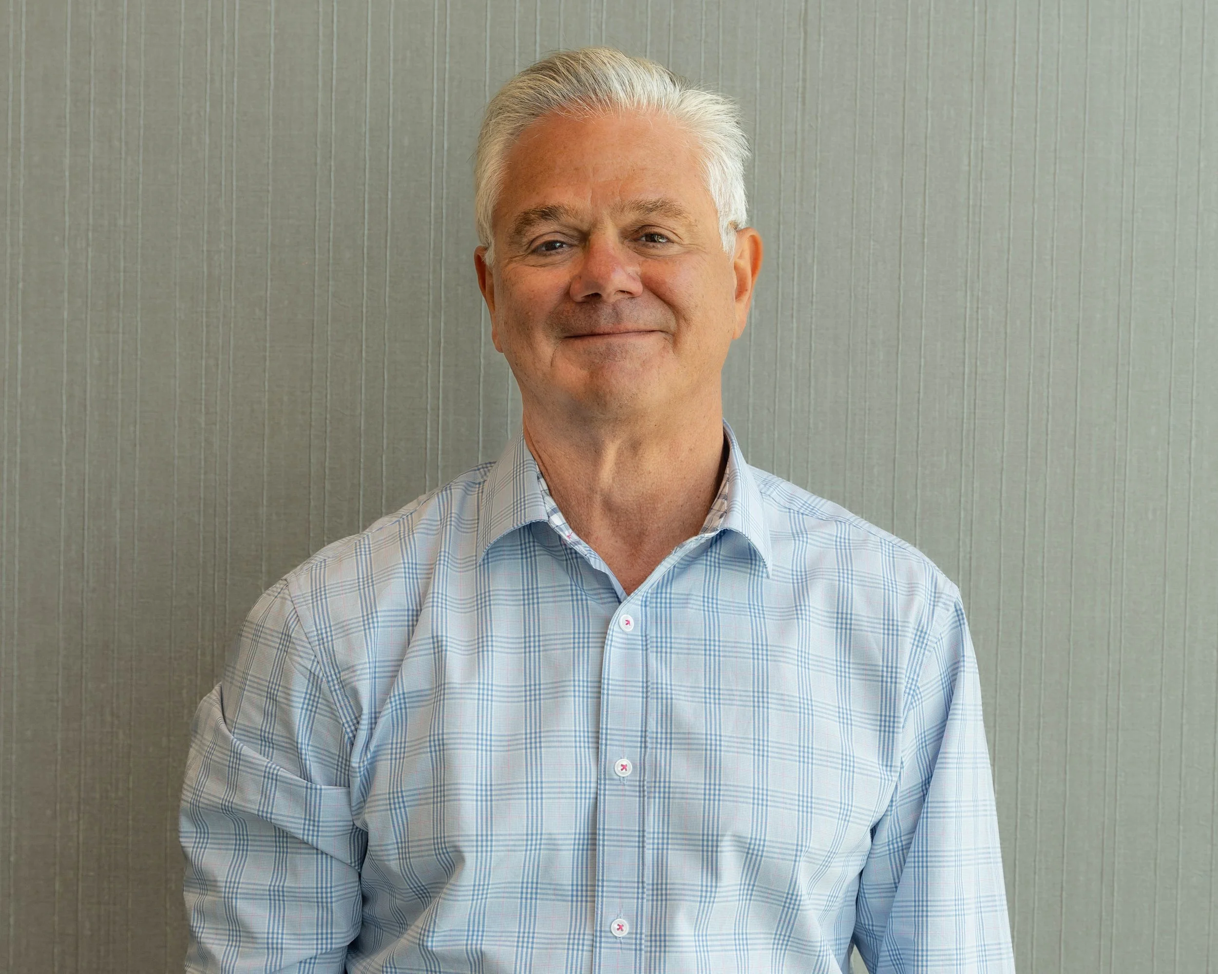 Smiling man with gray hair in front of blue background