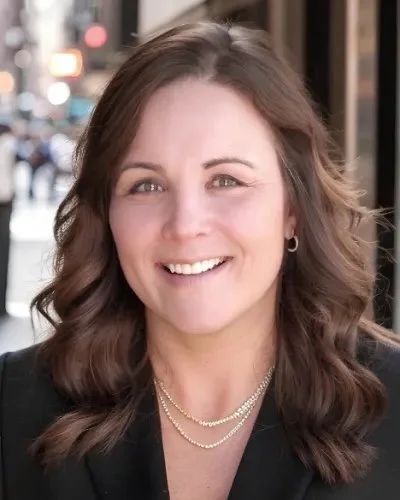 Black and white portrait of a smiling woman with long wavy hair, wearing a lace top.