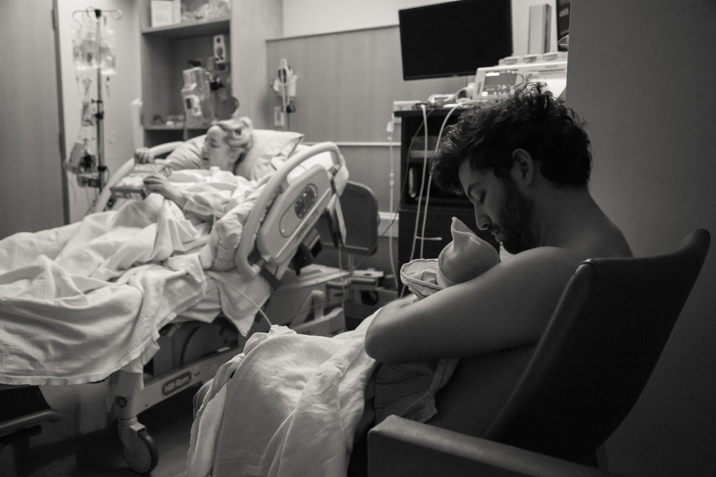 Rachel holds her baby while receiving stitches, keeping skin-on-skin contact for the first hour to help regulate Eliora’s body temperature.