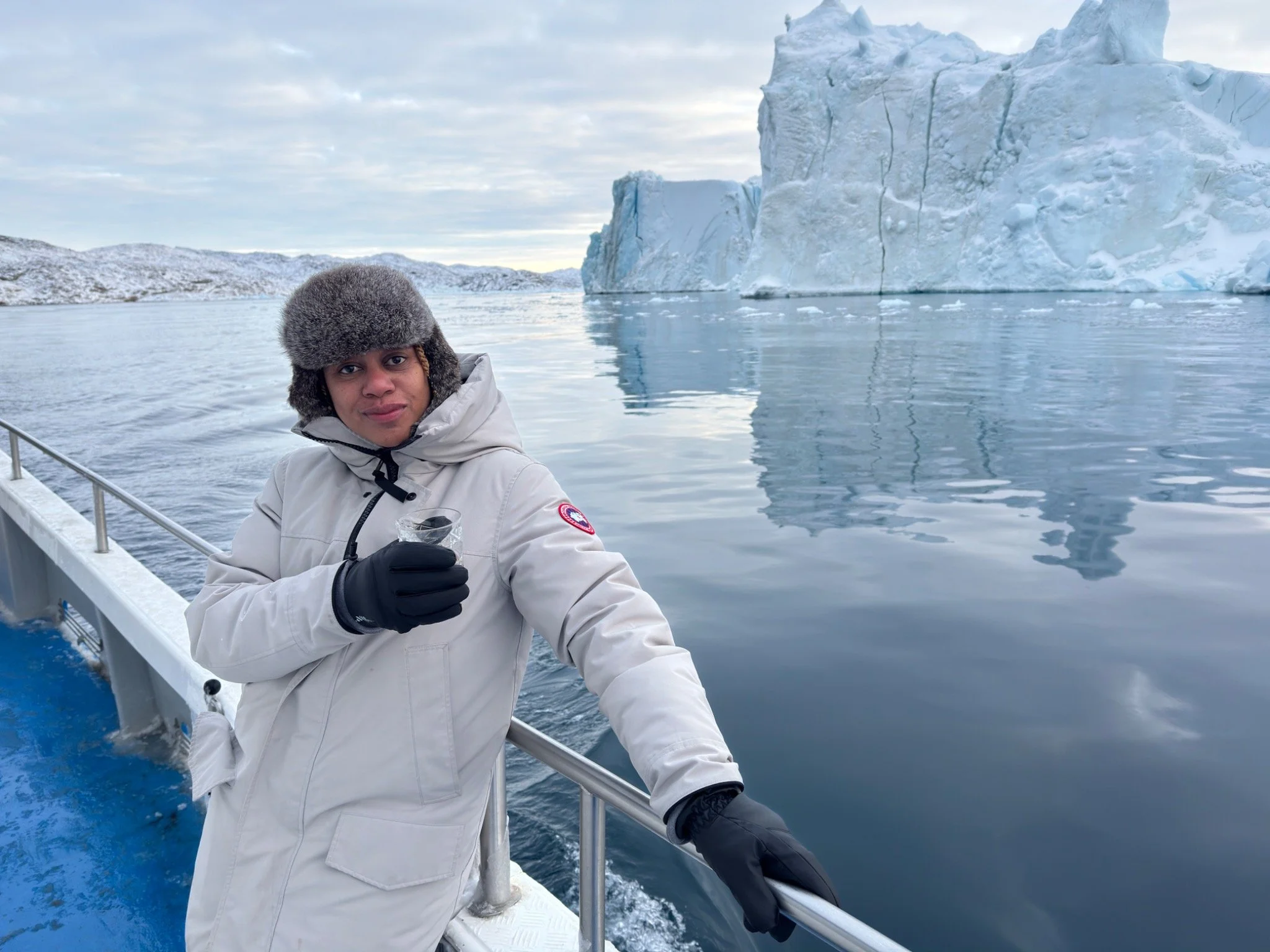Ebony on an iceberg cruise in Ilulissat, Greenland, with a massive iceberg behind her.