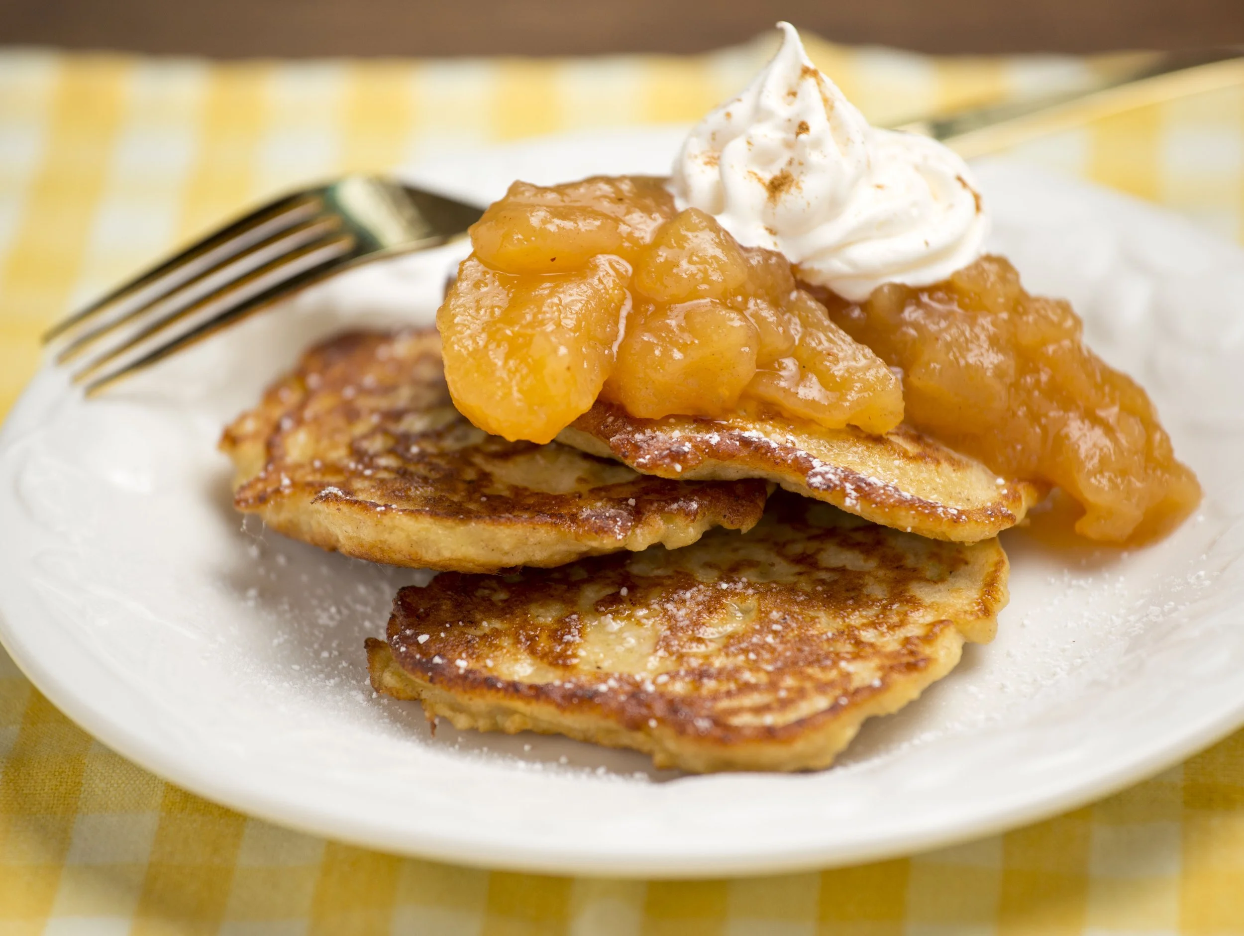 Plate of French toast topped with canned peaches, whipped cream, and powdered sugar.