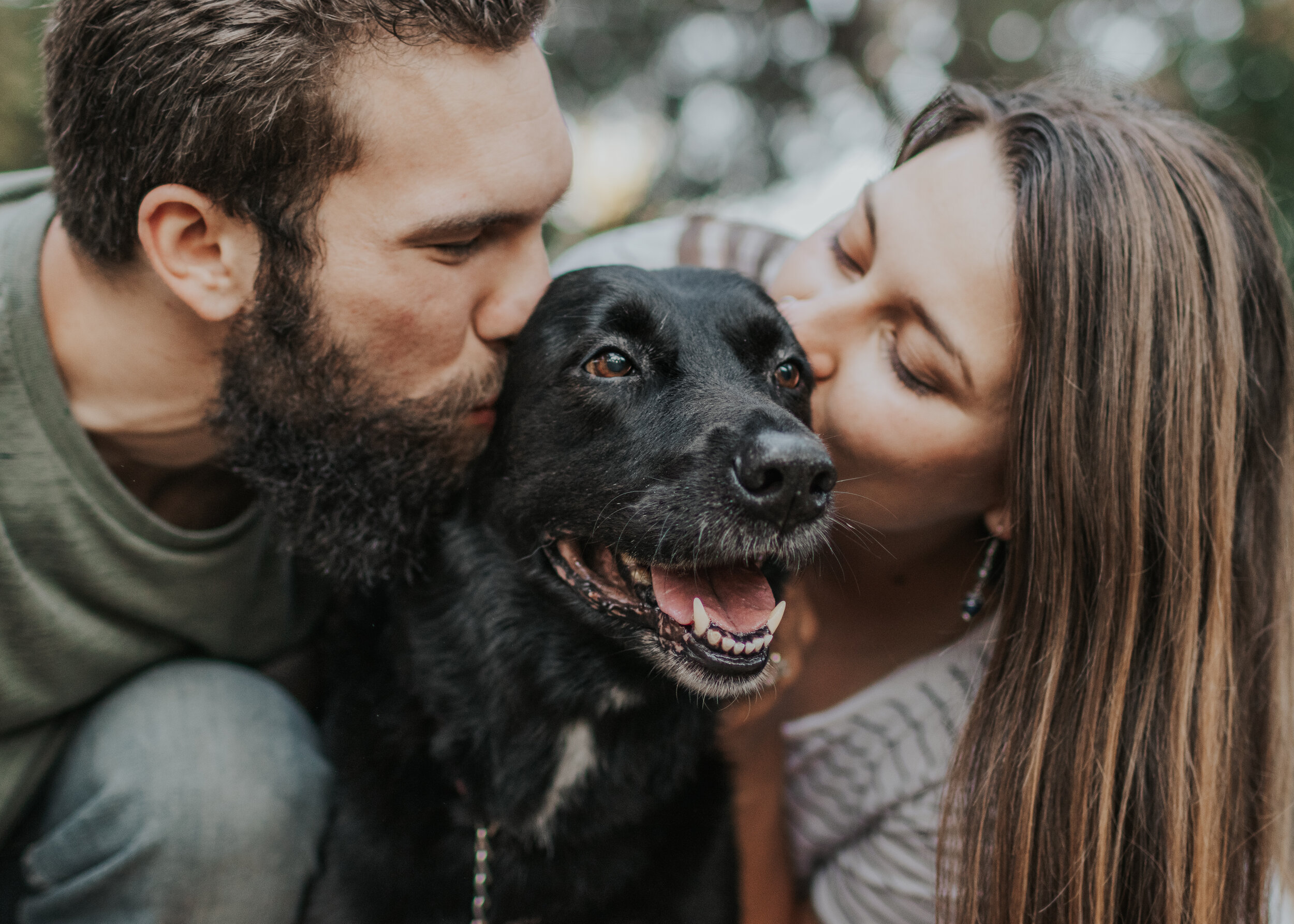 Couple kissing black lab during engagement session.