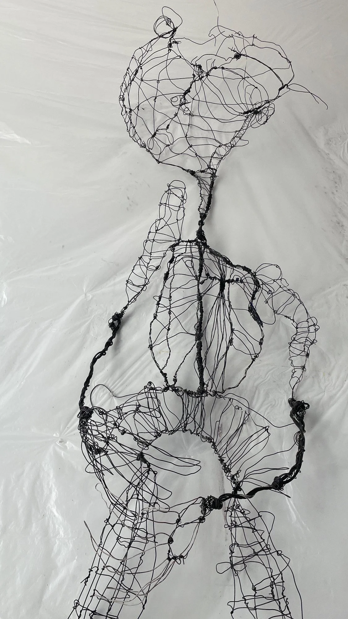 Wire sculpture of a person holding a large heart-shaped object