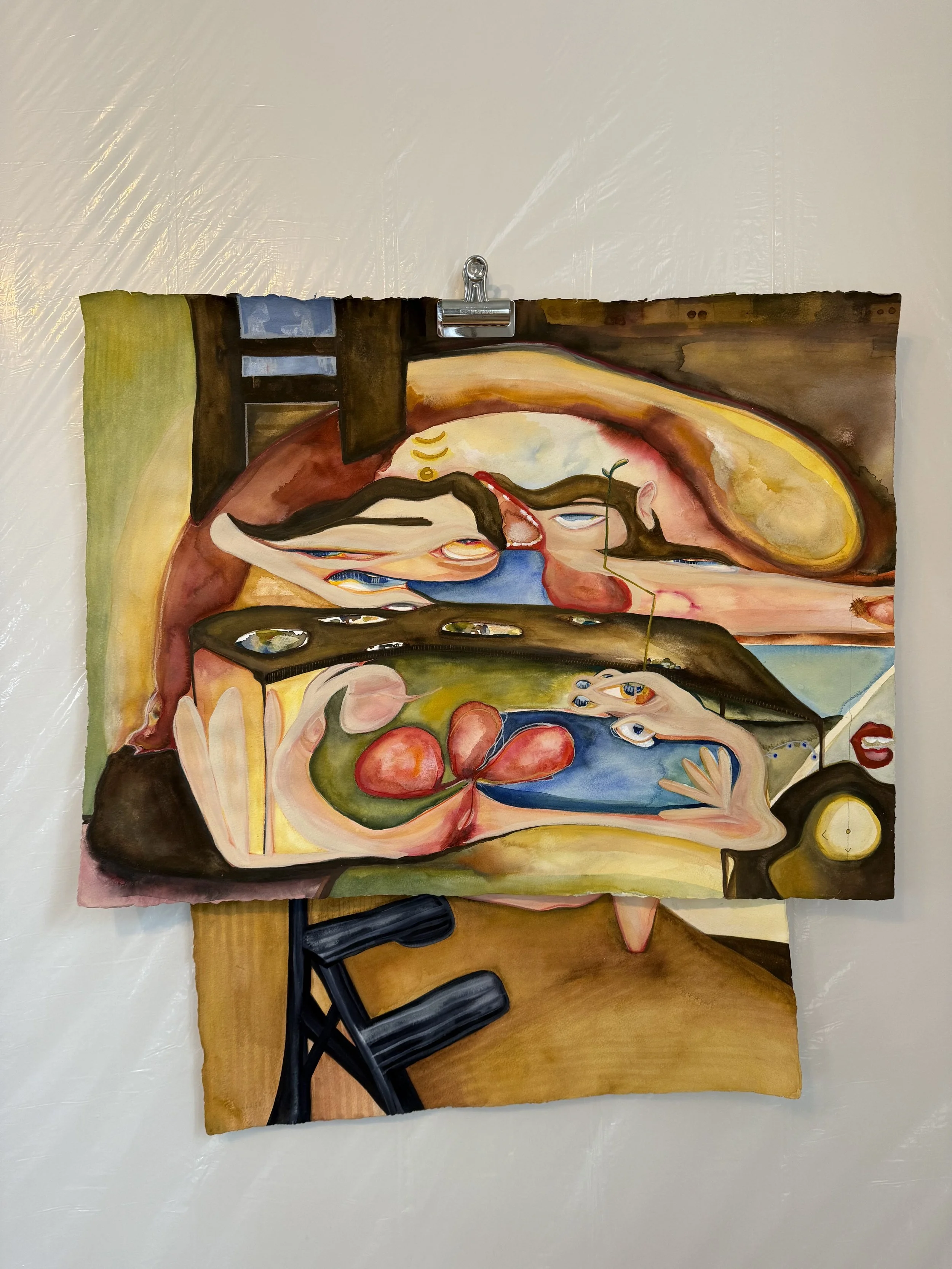 An abstract watercolor painting on paper hangsclip on a white wall, depicting a surreal scene with a woman resting, a fish, cherries, and whimsical elements in warm colors.