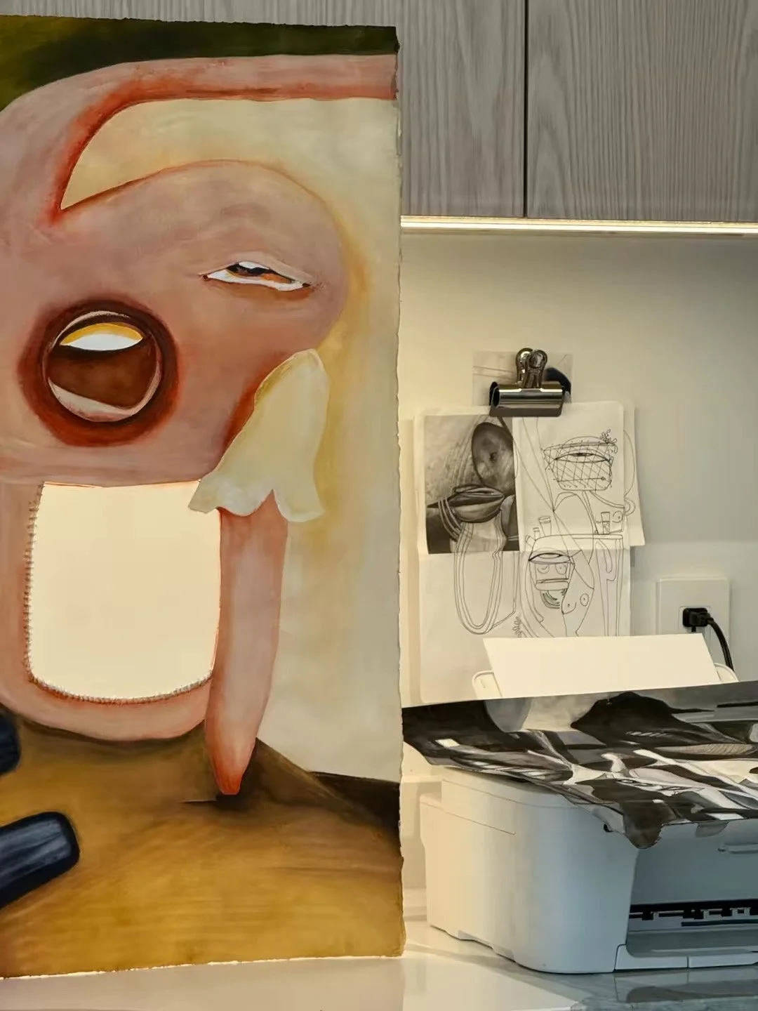 Mixed media art with a painted face of a person with a large open mouth, one eye closed and the other slightly open, with abstract elements surrounding the face, including a cherry, a cucumber, and a slice of melon, on the left side.
