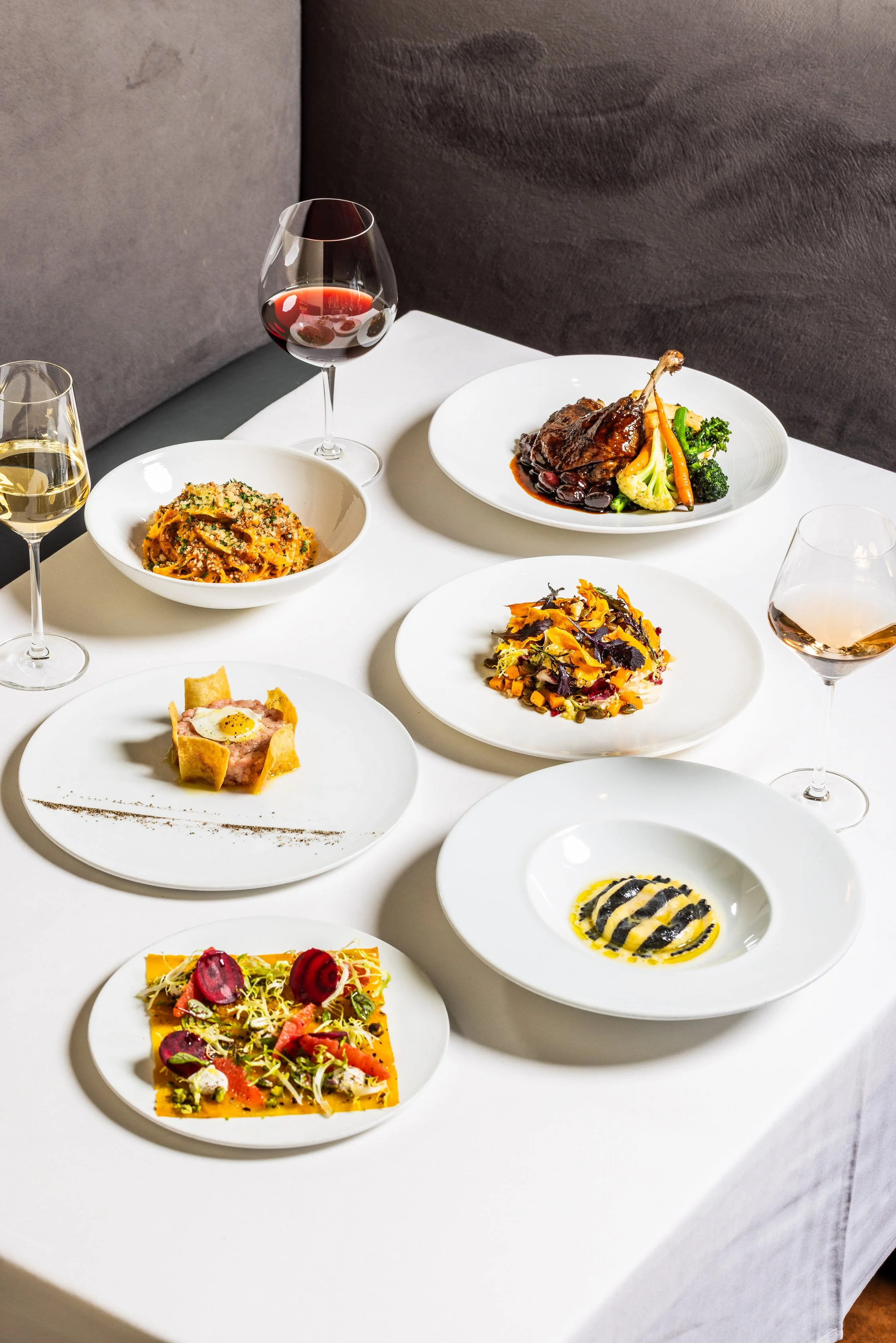 Elegant table setting with assorted gourmet dishes and glasses of red and white wine.