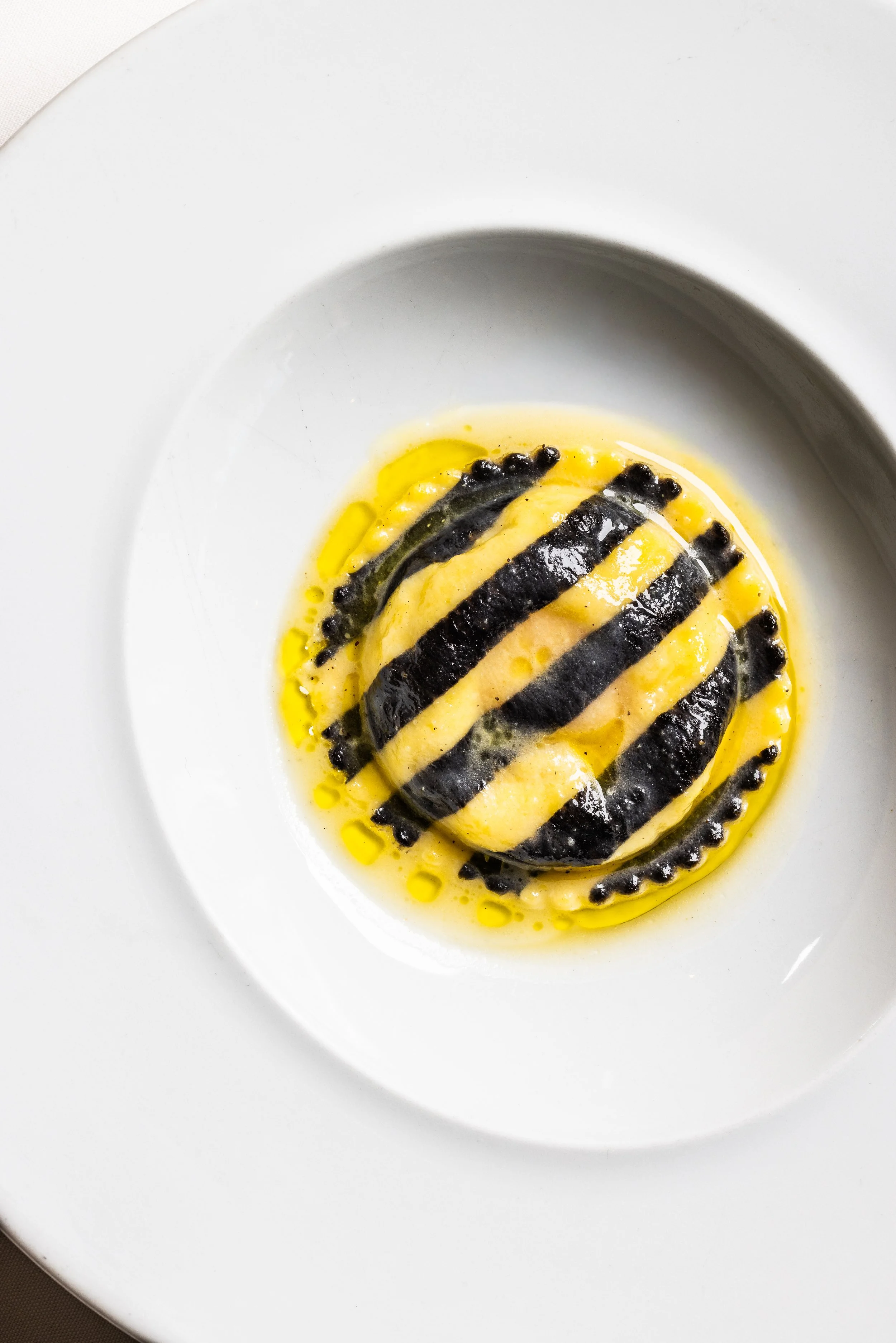 A gourmet dish with sliced black truffle drizzled with olive oil, served on a white plate.