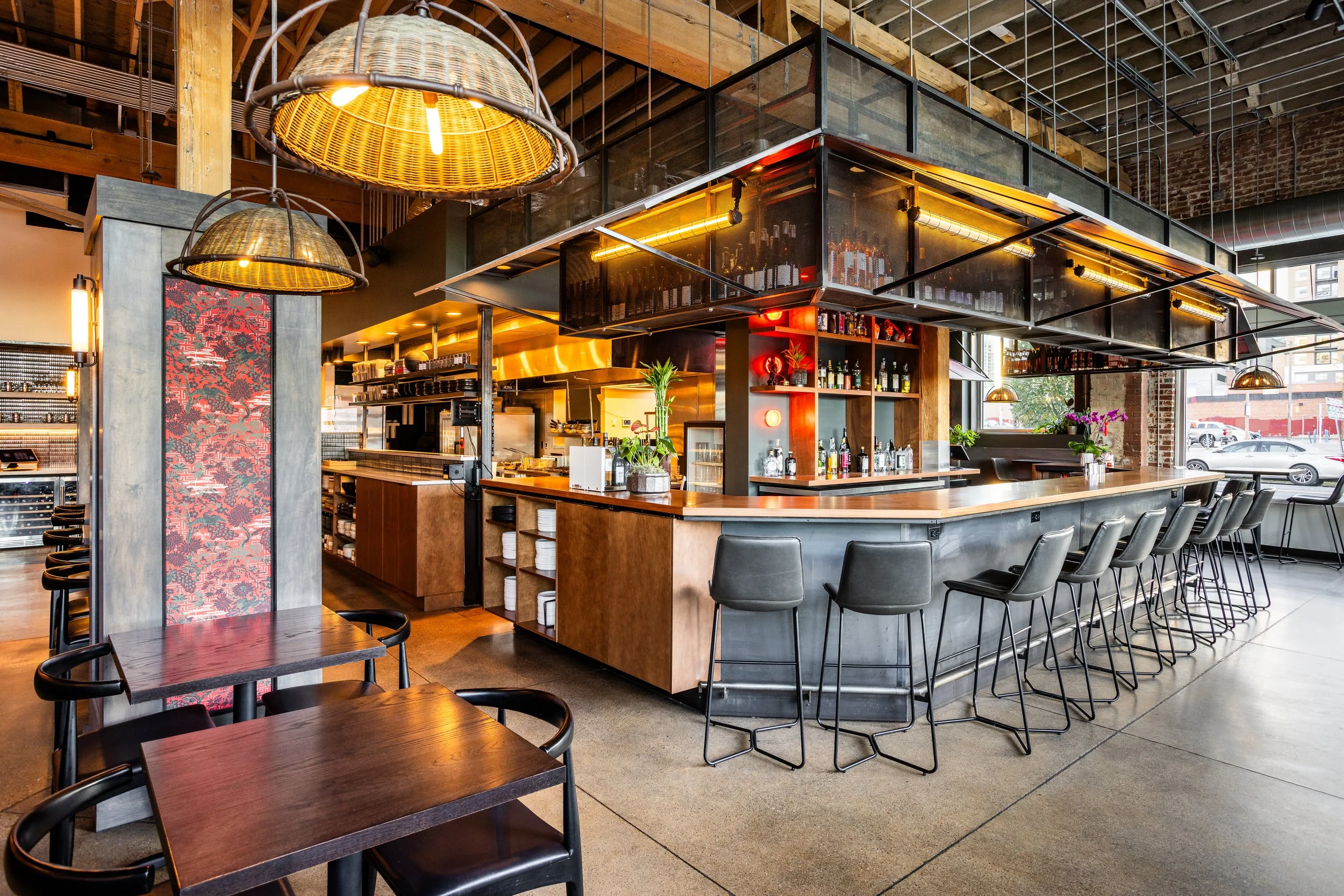 Modern restaurant with an open bar area, black chairs, and tropical decor accents.