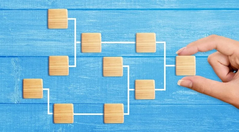 Image of databases as wooden blocks linked together with a hand placing the blocks