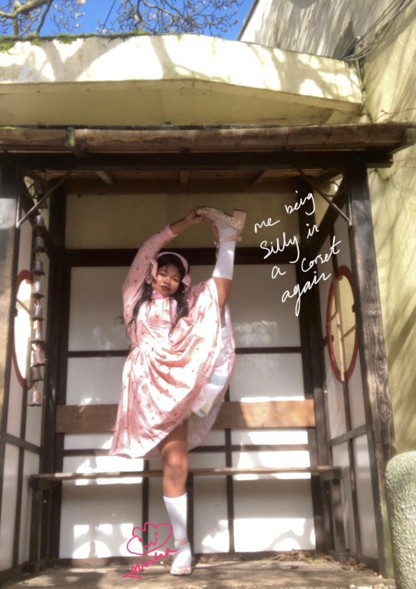 Alisha Lawrence in a flexible pose in a sweet lolita Peter rabbit dress in a Japanese garden to show how comfortable a victorian corset can be