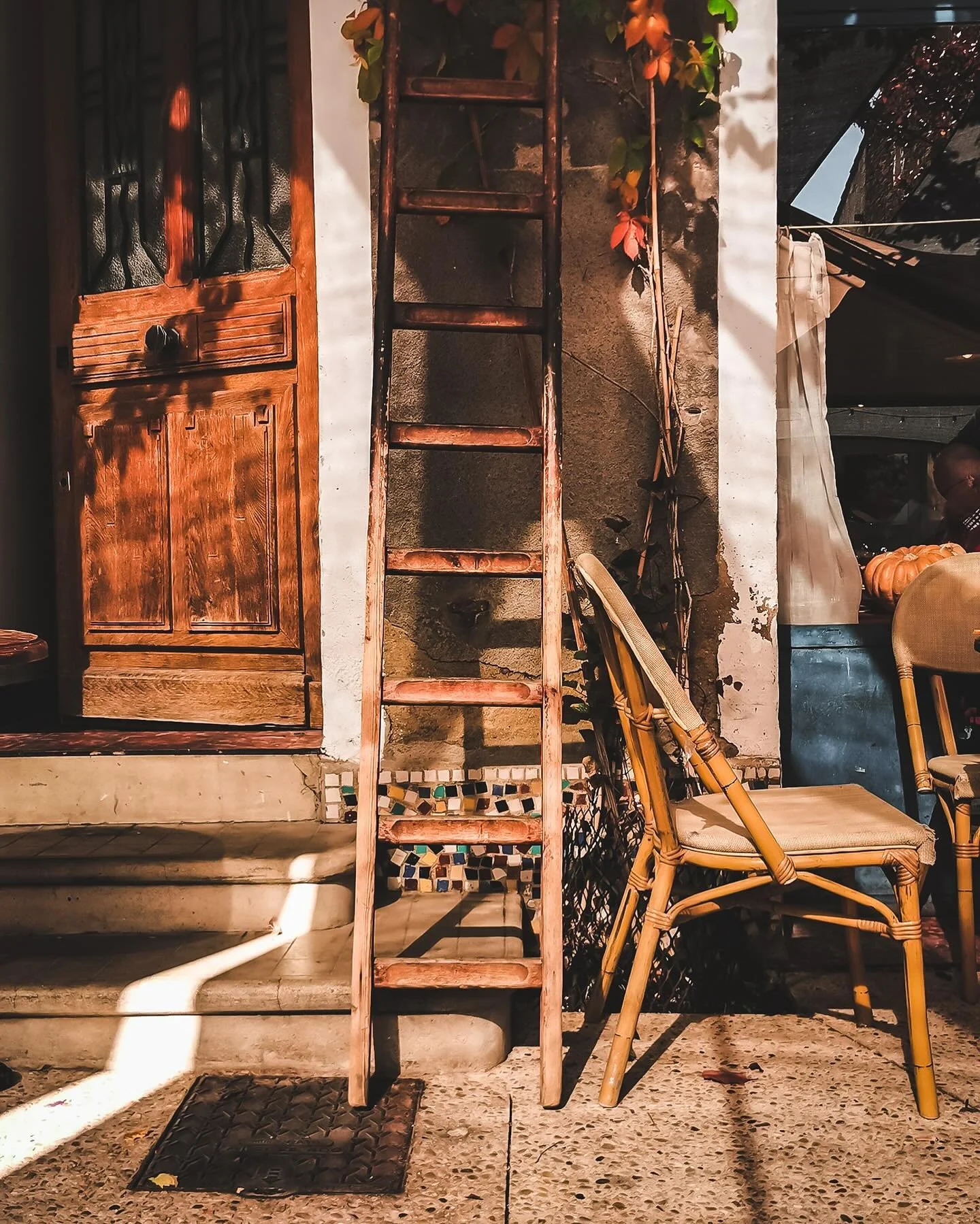 Old blue stucco building with two black wooden windows, one on each floor, with peeling paint and a weathered appearance, casting shadows on the wall.