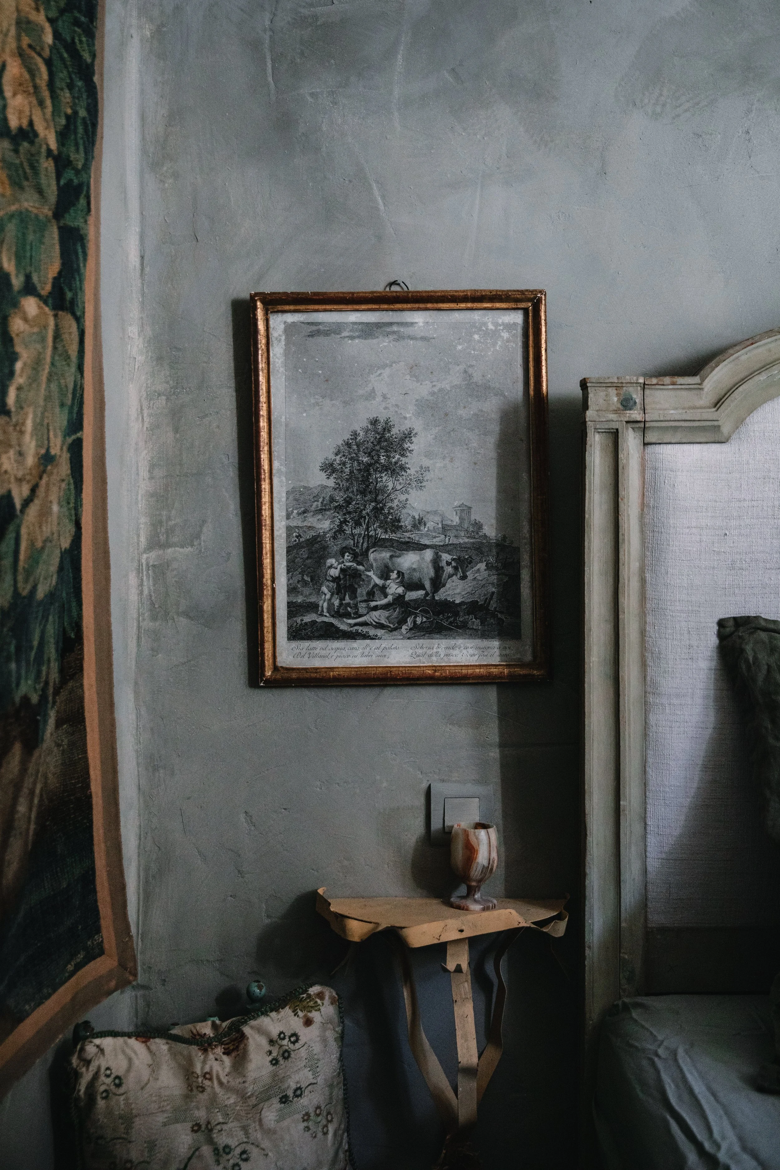 A black and white framed picture of children and a cow outdoors on a wall in a vintage-style room.