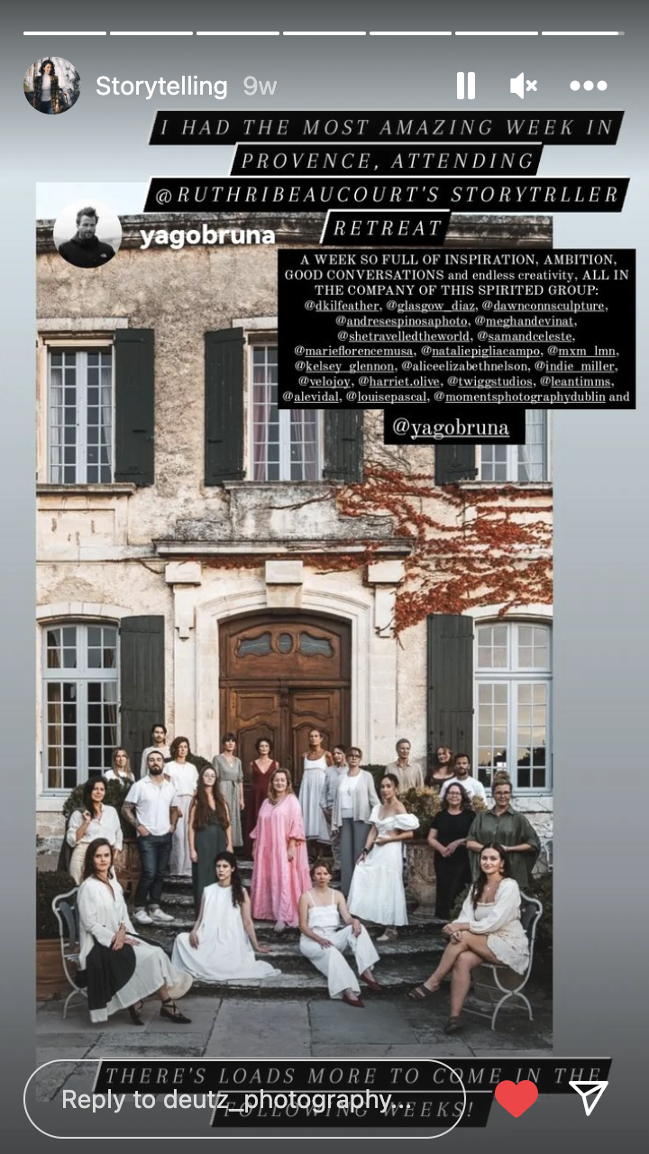 Group photo outside a historic building in Provence, featuring women in white dresses and others in casual and semi-formal attire, with an autumn tree and window shutters in the background.