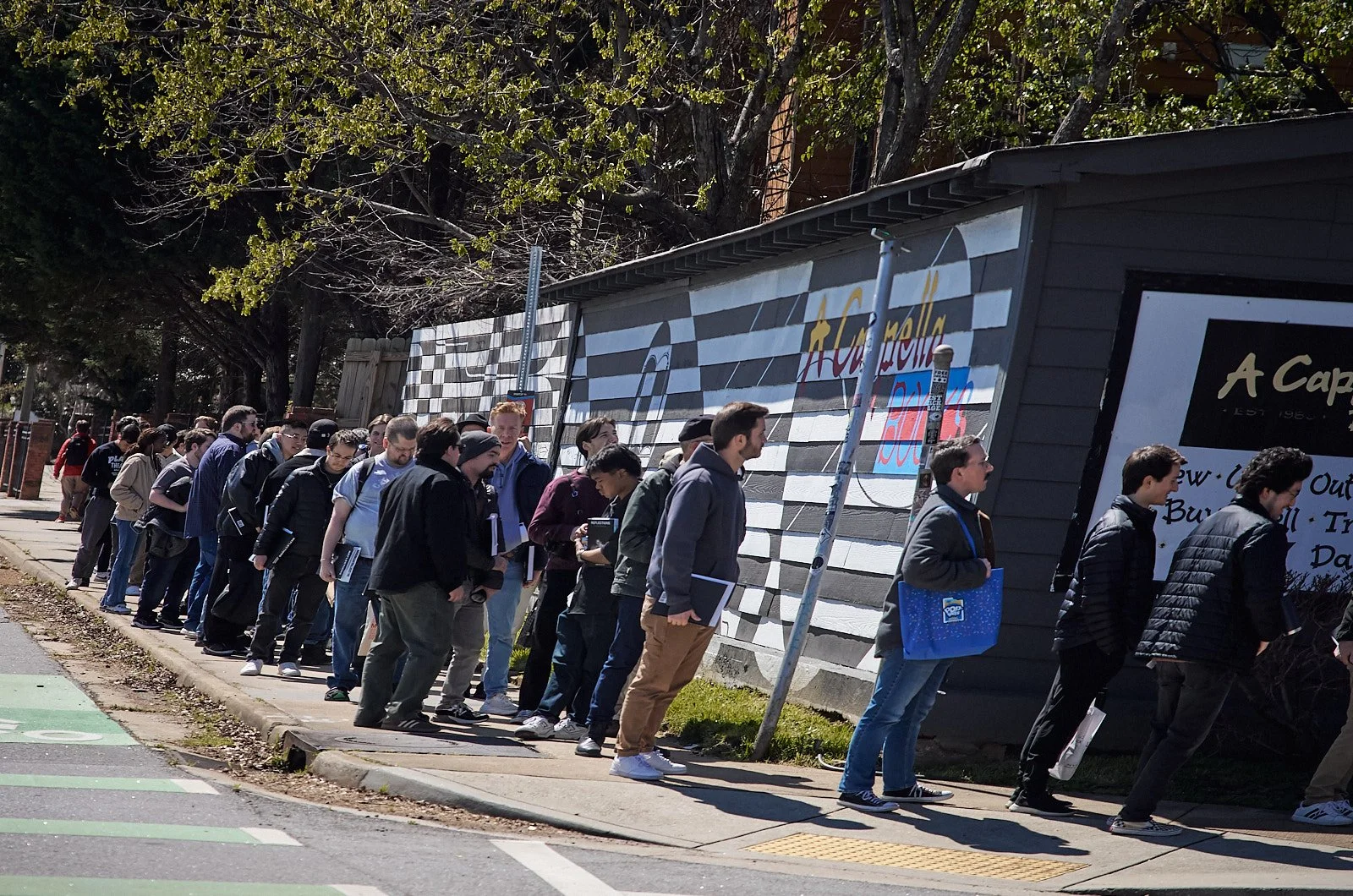 People standing in line outside a building, waiting their turn.
