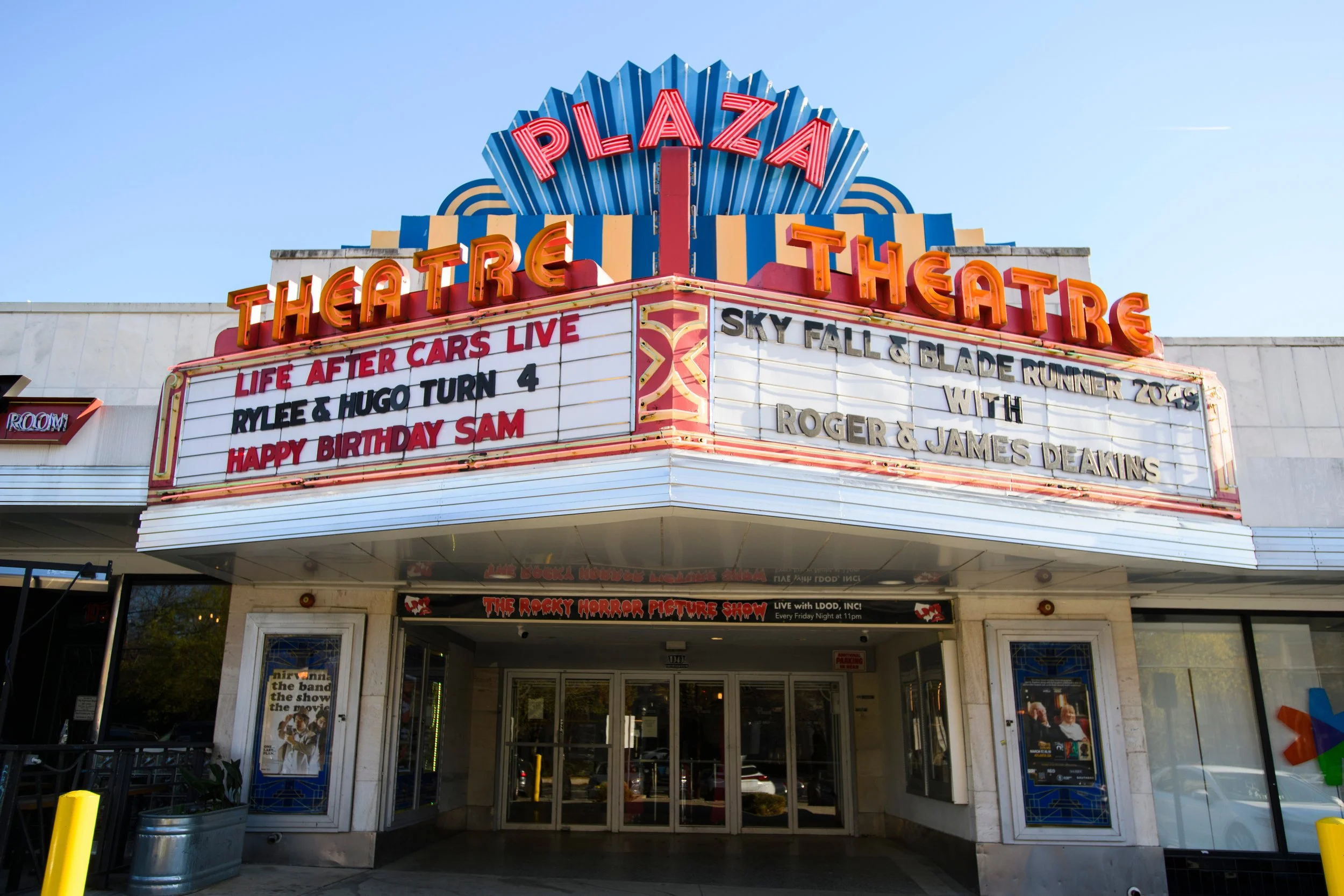 The marquee of a theater with neon sign text reading 'Theatre' and an upcoming show titled 'Life After Cars Live' starring Rylee & Hugo Turn 4 and celebrating Sam's birthday. The marquee also displays upcoming events including 'Sky Fall & Blade Runne