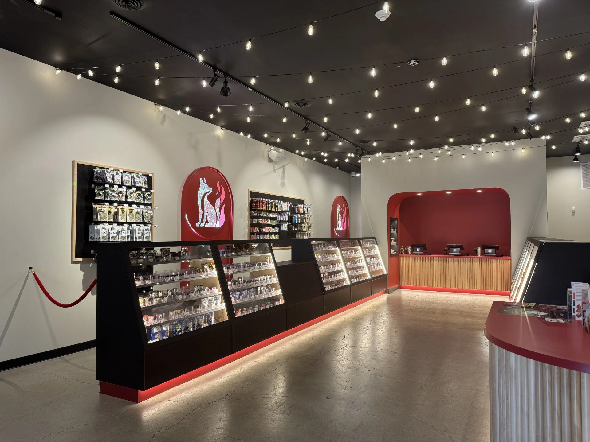 Interior of a retail store with display cases, shelves of products, decorative lighting, and a reception or checkout counter.