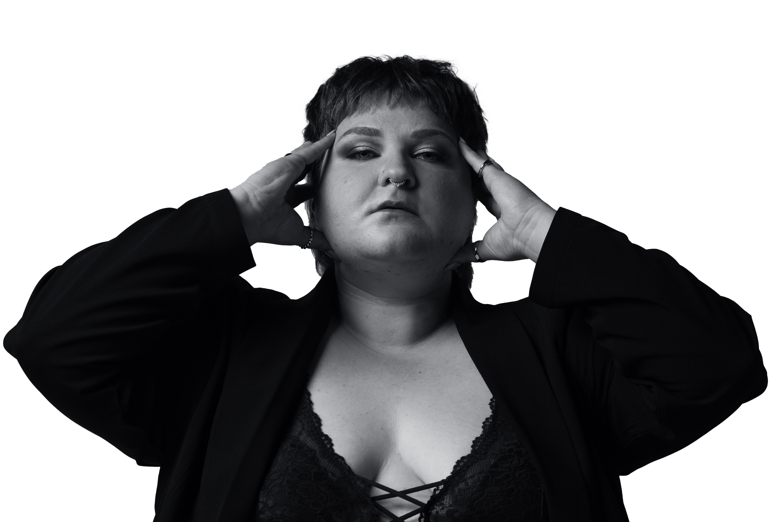 A close up black and white image of a plus sized woman with her hands on either side of her head looking directly into the camera