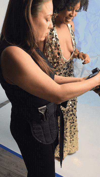 Two women in a photography studio looking at the content they created on the back of a camera