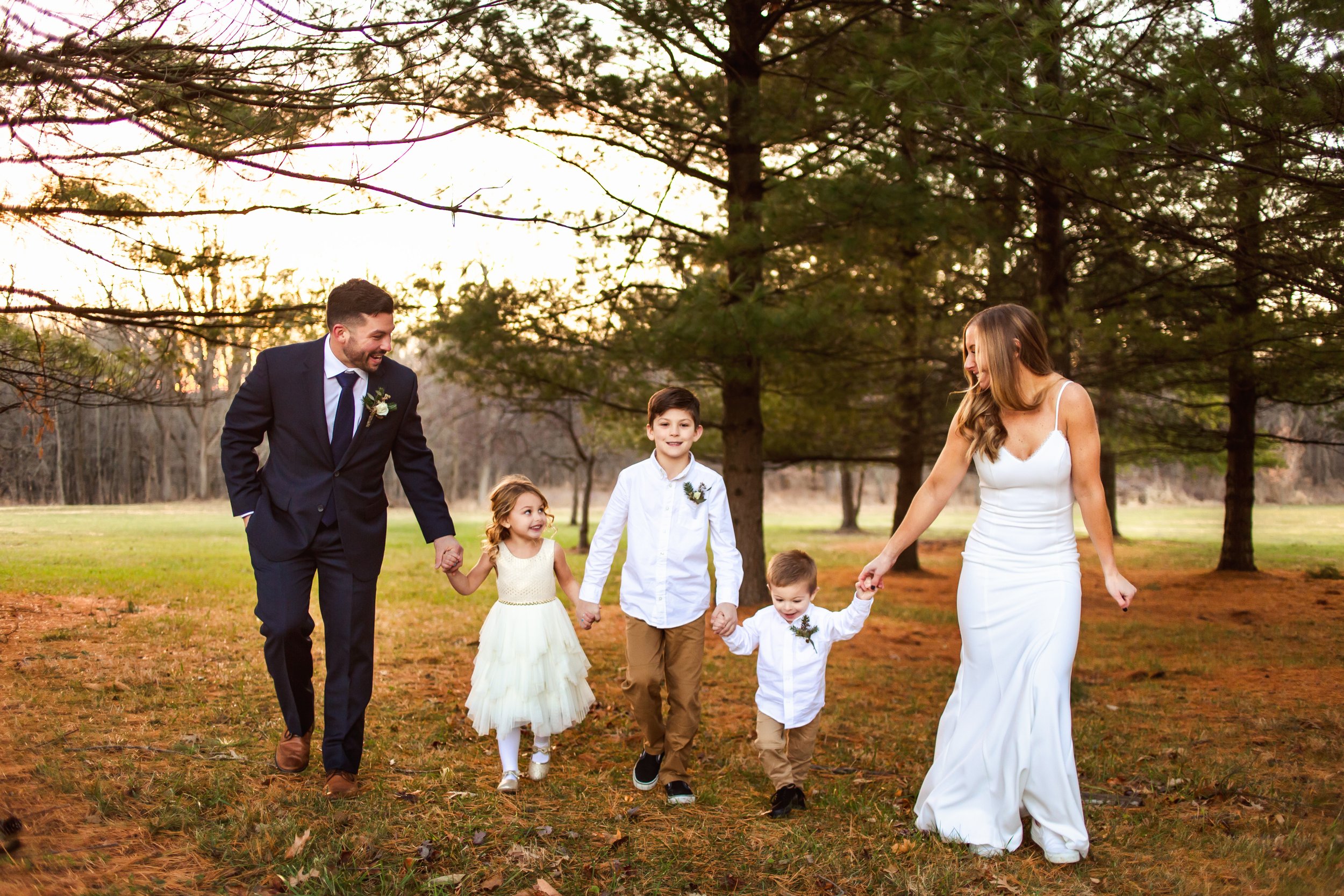  Bride and groom walk with their children while holding hands at Ironwood on the Vermillion by Teala Ward Photography. wedding with kids babies #tealawardphotography #tealawardweddings #LaSalleIllinois #IronwoodontheVermillion #weddingphotographyIL 