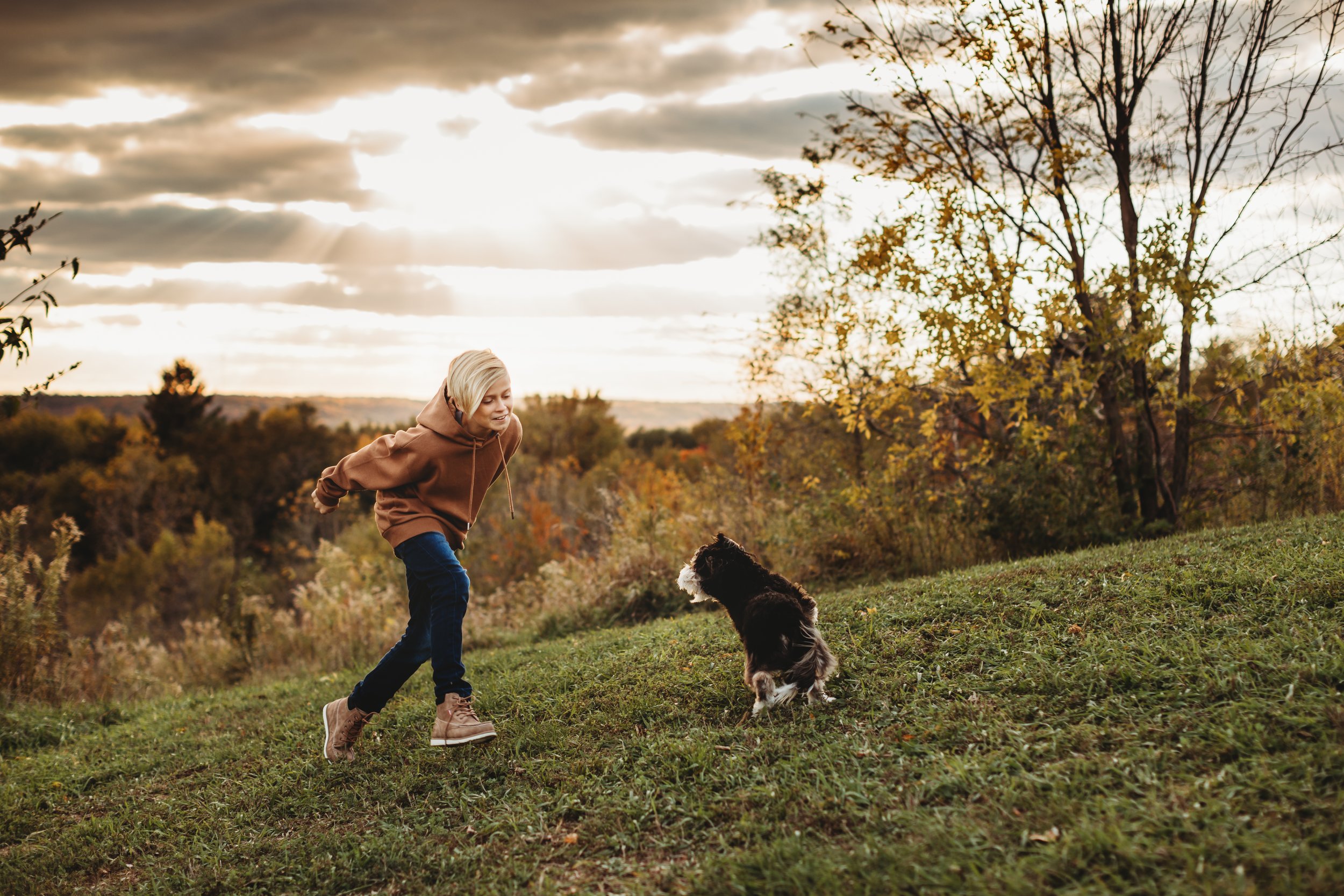  A young boy runs around a grass hill with his dog in Spring Valley, IL captured by Teala Ward Photography. Spring Valley Photog #tealawardphotography #tealawardfamilies #springvalleyillinois #springvalleyphotographers #Illinoisfamilyphotographer 