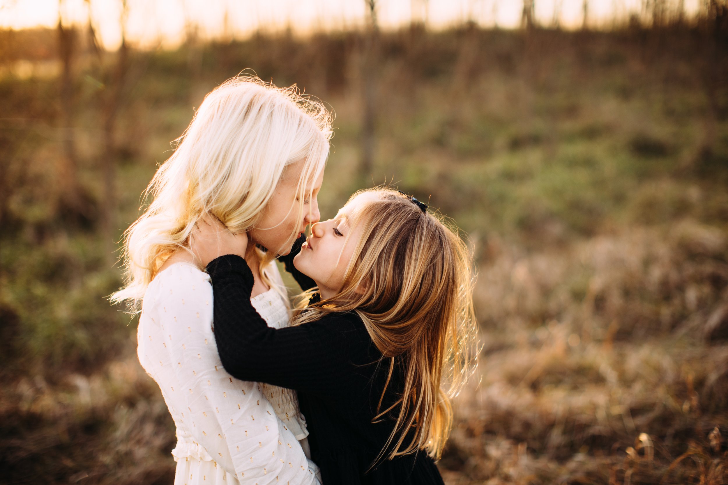  In a grass field at Starved Rock State Park, two sisters kiss each other on the mouth by Teala Ward Photography. sister kisses #TealaWardPhotography #TealaWardFamilies #StarvedRockStatePark #BuffaloRockPhotographers #UticaIllinoisphotographers 