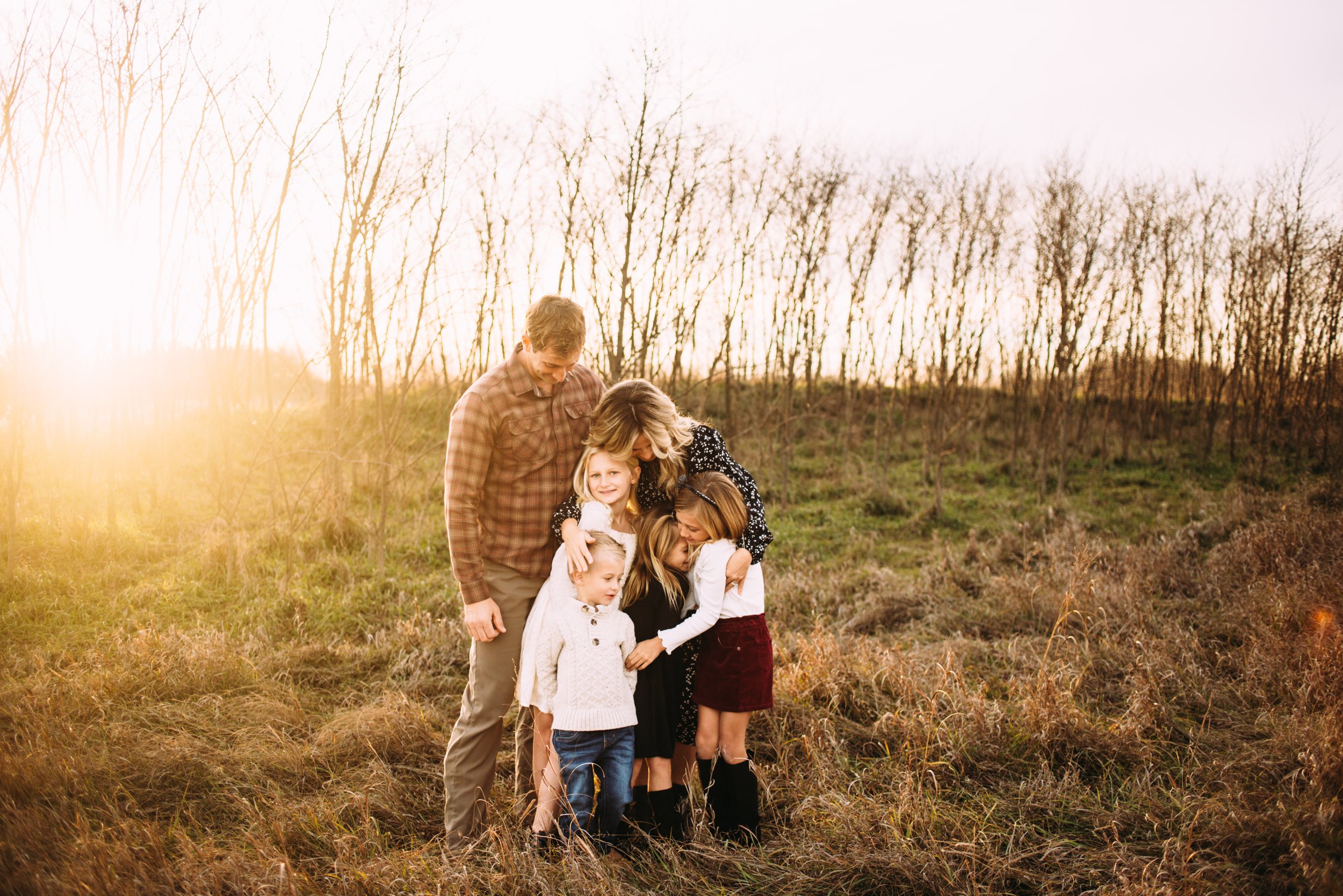  Teala Ward Photography captures a family portrait with a sunburst behind them as they hug one another. hugging family sunburst #TealaWardPhotography #TealaWardFamilies #StarvedRockStatePark #BuffaloRockPhotographers #UticaIllinoisphotographers 