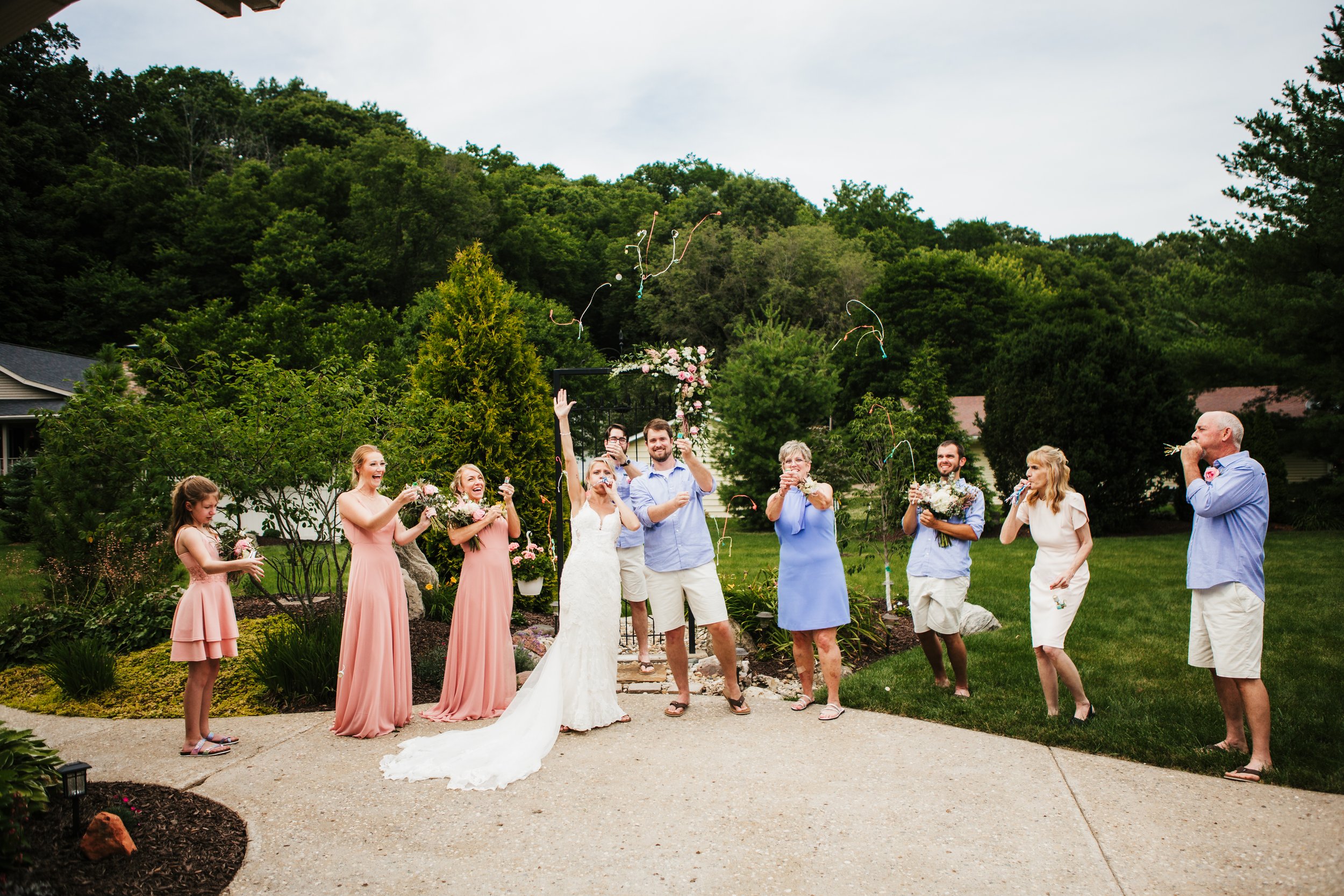  Bridal party celebrates after an intimate at home wedding ceremony . bride wore a long trained lace dress   pink bridesmaid dresses groom in shorts casual #TealaWardPhotography #illinoisphotographer #princetonillinois #weddingphotographer #intimatew