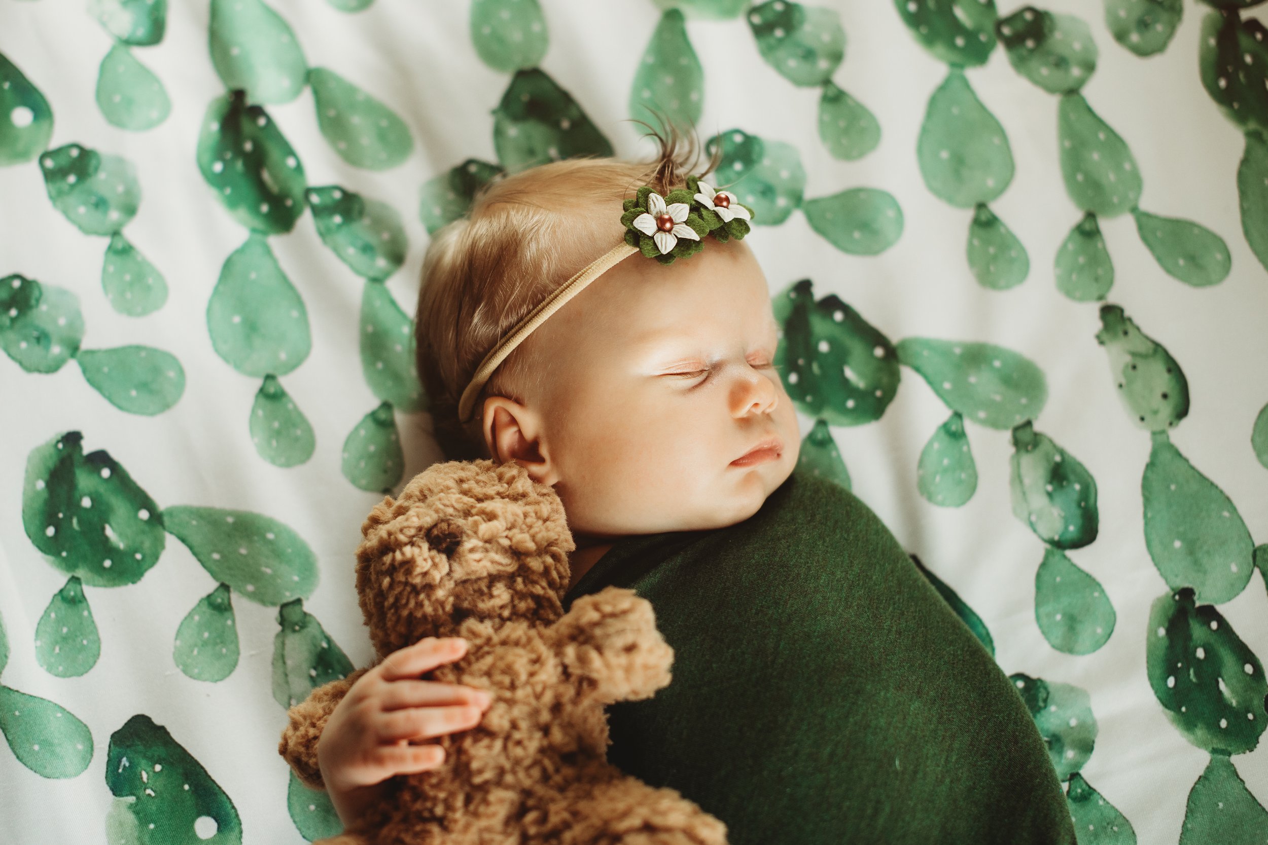  Newborn baby snuggles her teddy bear at her newborn photo shoot. cactus sheets floral headband brown fuzzy teddy bear photos at home Teala Ward Photography in Princeton Illinois #TealaWardPhotography #illinoisphotographer #princetonillinois  