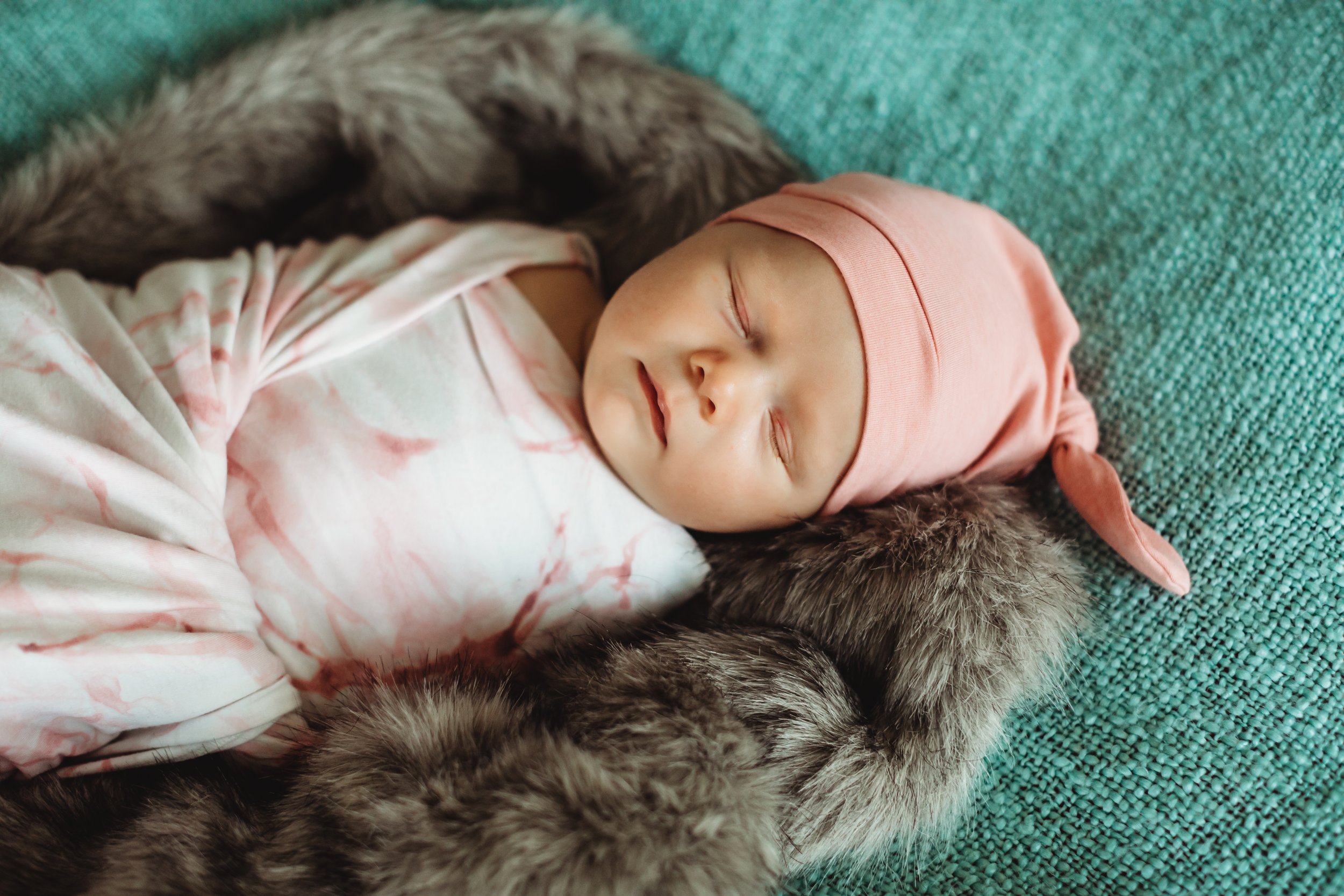  Newborn baby girl swaddled in a pink floral wrap with a pink beanie. fuzzy rug green blanket newborn photos at home Teala Ward Photography in Princeton Illinois #TealaWardPhotography #illinoisphotographer #princetonillinois  